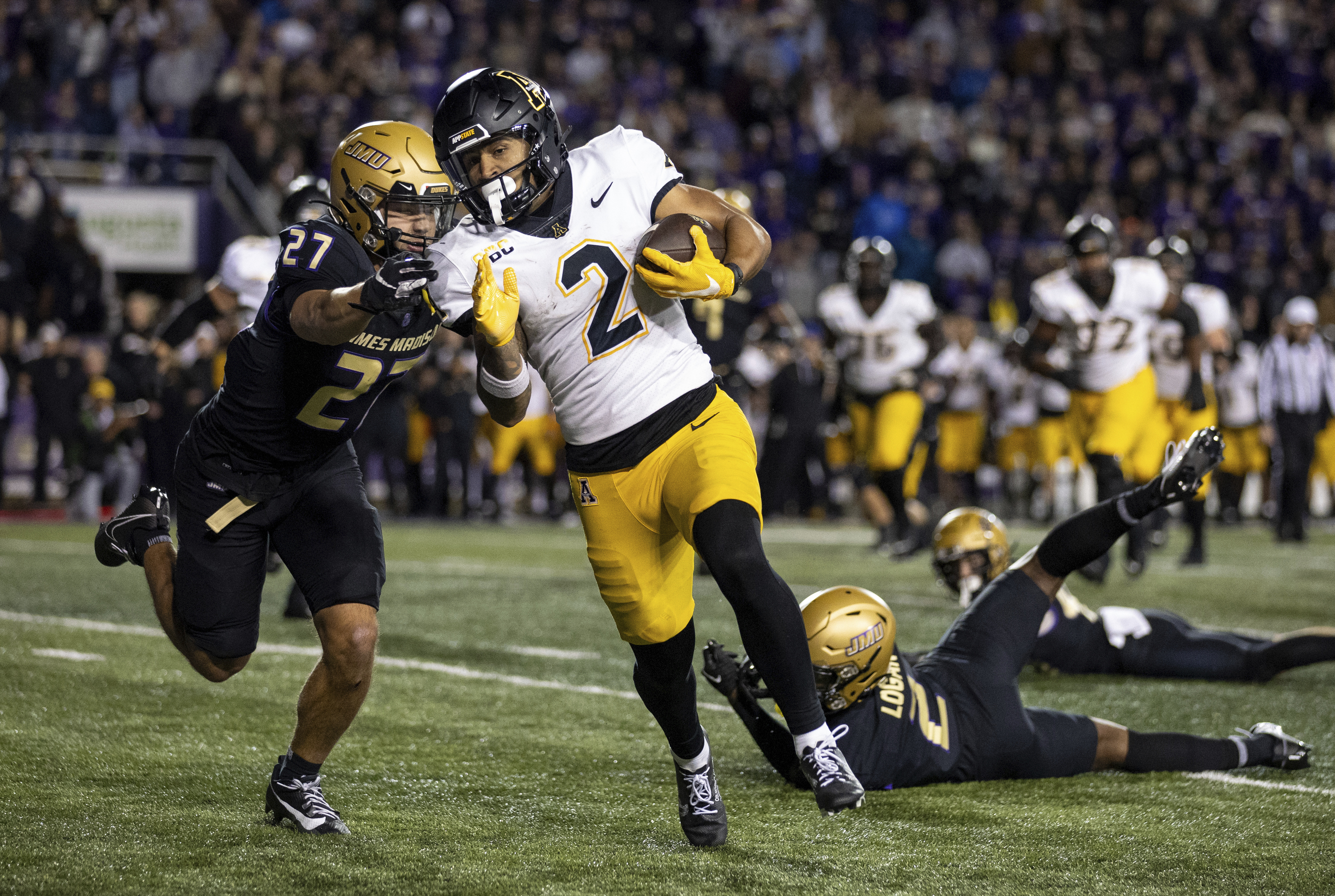 Appalachian State wide receiver Kaedin Robinson (2) tries to outrun James Madison safety Jacob Thomas (27) after shedding cornerback Chauncey Logan (2) and linebacker Noah Holmes, right, on his way to scoring the game-winning touchdown during overtime of an NCAA college football game in Harrisonburg, Va., Saturday, Nov. 18, 2023. 