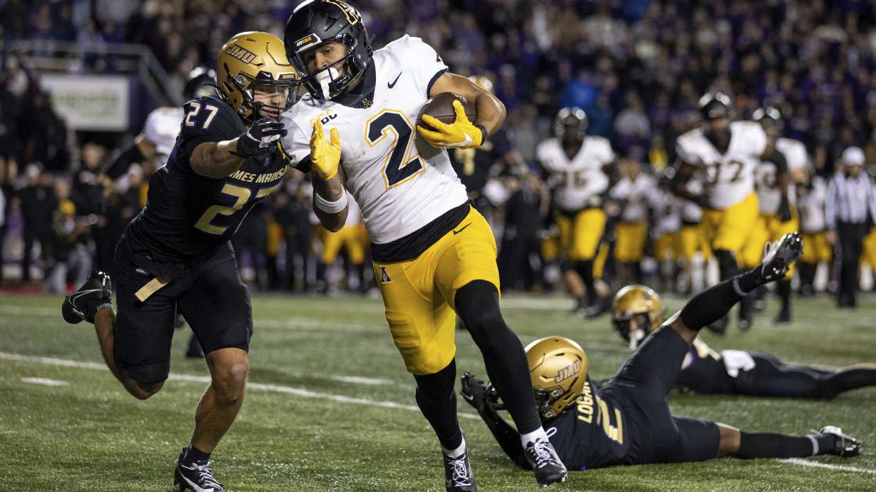 Appalachian State wide receiver Kaedin Robinson (2) tries to outrun James Madison safety Jacob Thomas (27) after shedding cornerback Chauncey Logan (2) and linebacker Noah Holmes, right, on his way to scoring the game-winning touchdown during overtime of an NCAA college football game in Harrisonburg, Va., Saturday, Nov. 18, 2023.