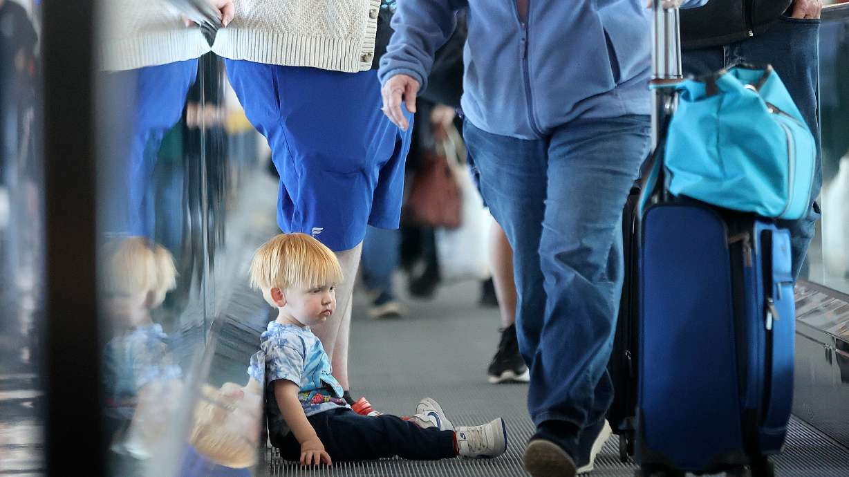 Walter Zollinger, 2, rides on the moving walkway as travelers pass him in the newly opened area of Concourse A at Salt Lake City International Airport in Salt Lake City on Oct. 31. The airport is expected to be busy ahead of Thanksgiving this week.