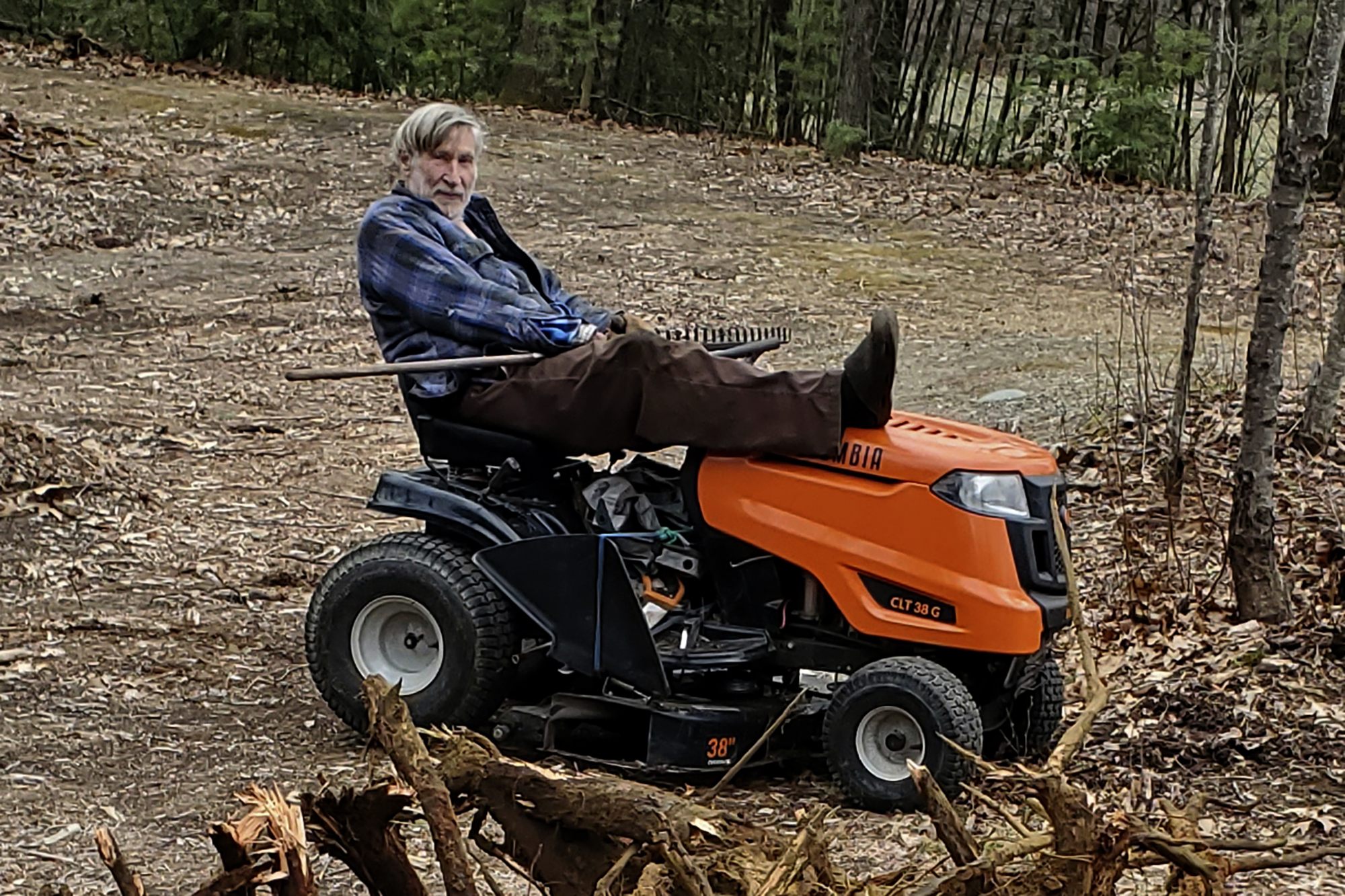 Geoffrey Holt rests his leg on top of his riding mower in Hinsdale, N.H., on April 4, 2020. Holt left the town of Hinsdale nearly $4 million when he died last June. 