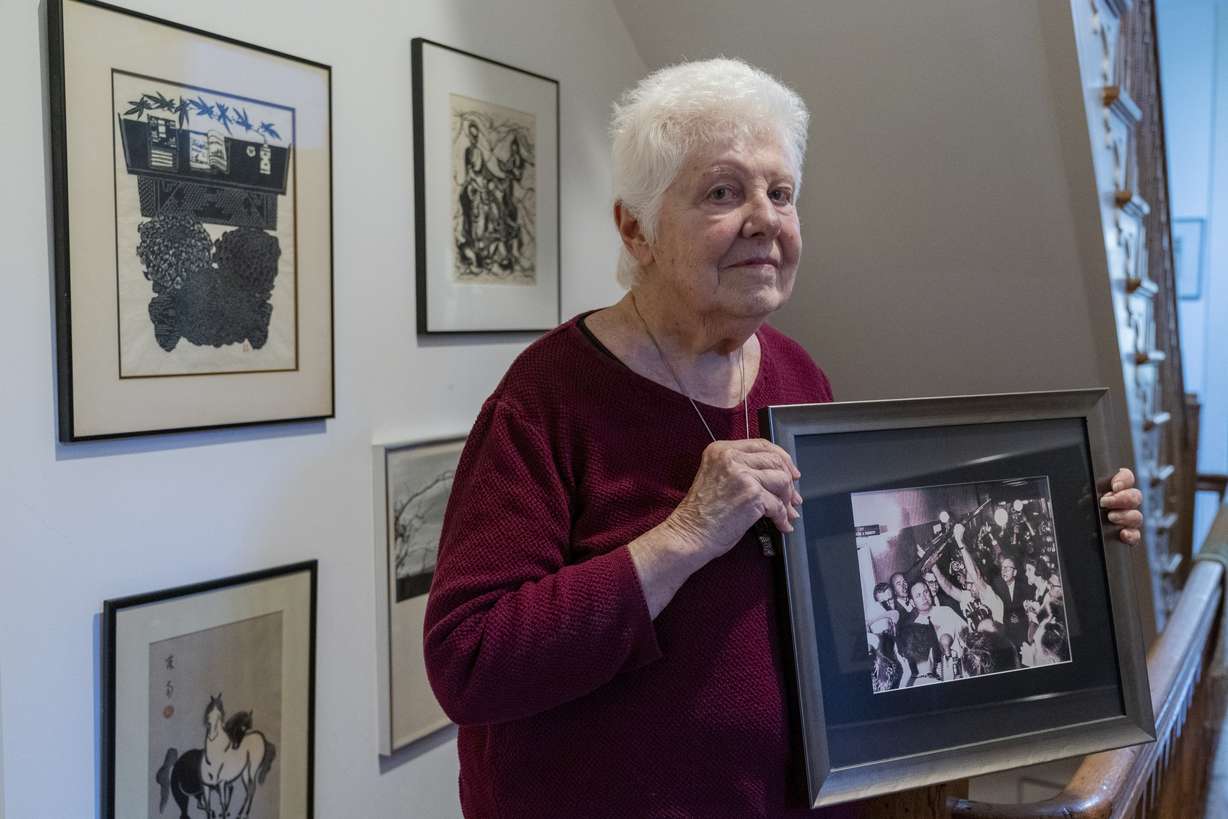 Peggy Simpson holds a photograph of law enforcement carrying Lee Harvey Oswald's gun through a hallway packed with reporters, Friday, at her home in Washington. Simpson, a former Associated Press reporter, is among the last surviving witnesses to the events surrounding the assassination of Kennedy are among those sharing their stories as the nation marks the 60th anniversary.