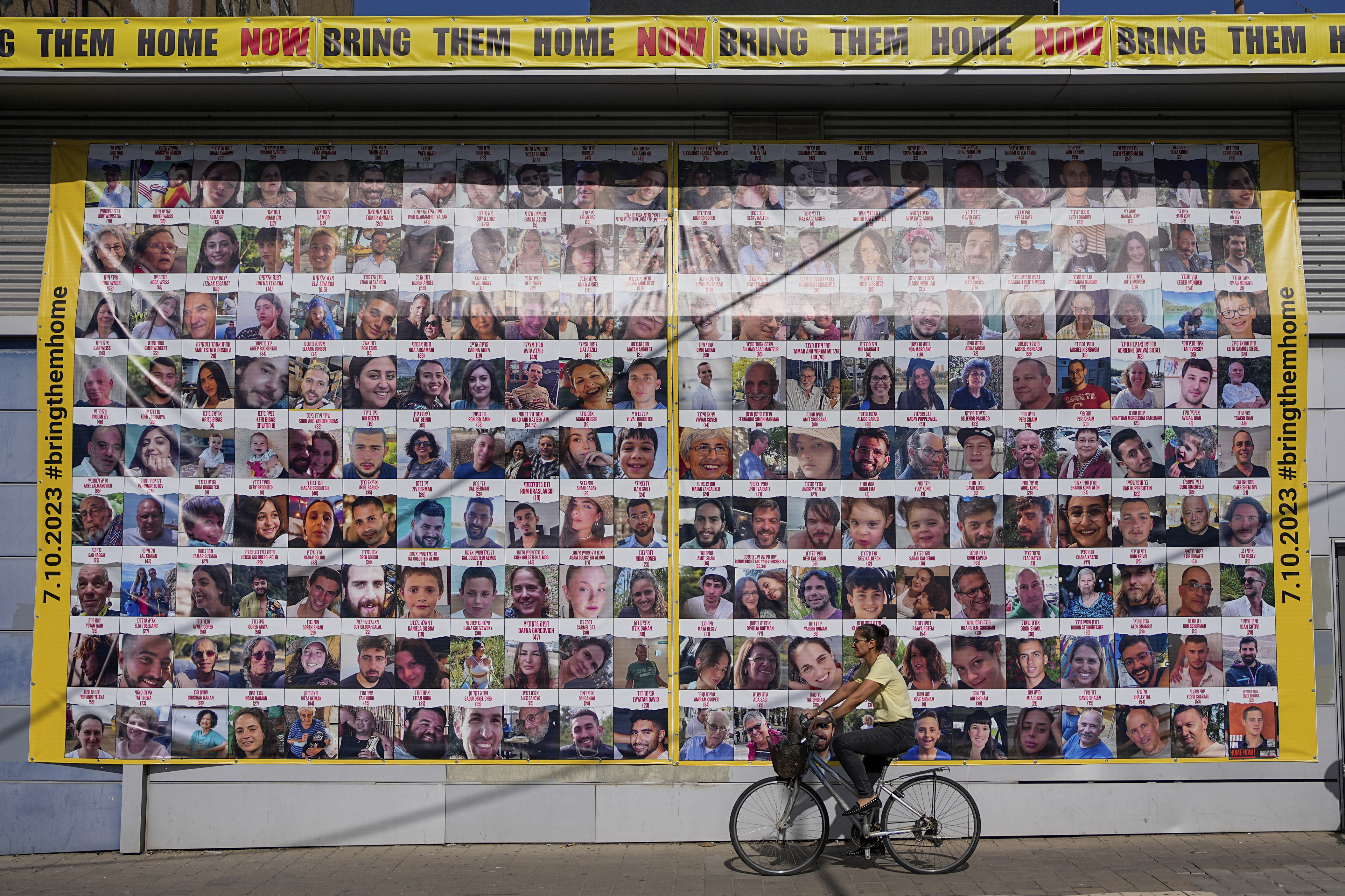 A woman cycles next to a billboard calling for the return of about 240 hostages who were abducted during the Oct. 7, Hamas attack on Israel. in Tel Aviv, Israel on Friday. Friday marks the start of a four-day cease-fire in the Israel-Hamas war, during which the Gaza militants pledged to release 50 hostages in exchange for 150 Palestinians imprisoned by Israel.