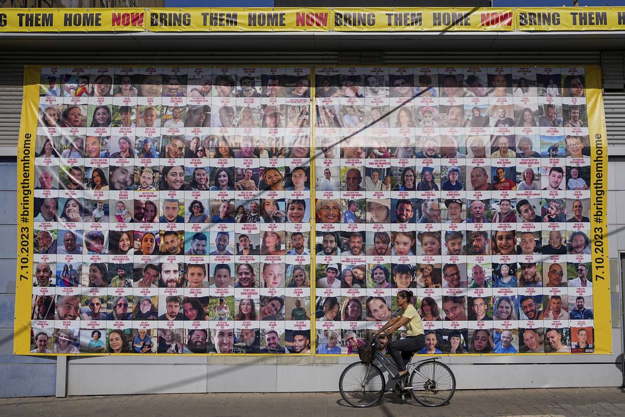 A woman cycles next to a billboard calling for the return of about 240 hostages who were abducted during the Oct. 7, Hamas attack on Israel. in Tel Aviv, Israel on Friday. Friday marks the start of a four-day cease-fire in the Israel-Hamas war, during which the Gaza militants pledged to release 50 hostages in exchange for 150 Palestinians imprisoned by Israel.