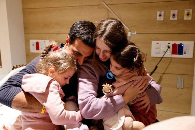 Aviv Asher, 2-year-old, her sister Raz Asher, 4-year-old, and mother Doron, react as they meet with Yoni their father and husband, after they returned to Israel to the designated complex at the Schneider Children's Medical Center, during a temporary truce between Hamas and Israel, in Petah Tikva, Israel, in this picture released on Saturday.