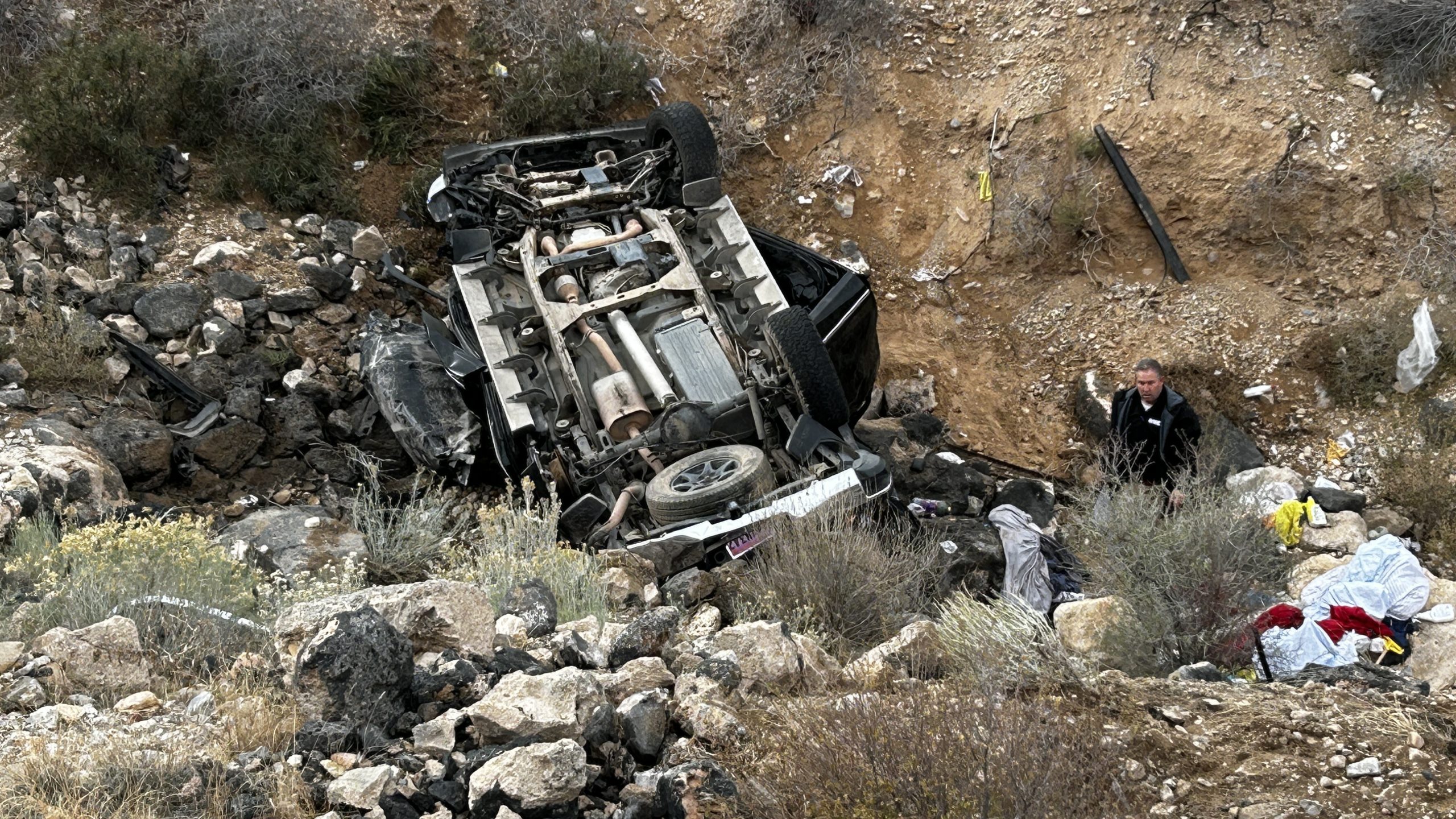 A medical examiner stands next to the wreck of a pickup truck that was found overturned in a ravine off Old Dixie Highway 91, in Shivwits, Washington County, on Friday. 