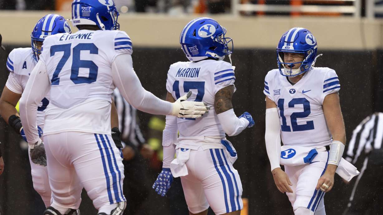 BYU quarterback Jake Retzlaff (12) and offensive lineman Caleb Etienne (76) celebrate with wide receiver Keelan Marion (17) after he scores a touchdown in the first half of an NCAA college football game against Oklahoma State Saturday, Nov. 25, 2023, in Stillwater, Okla.