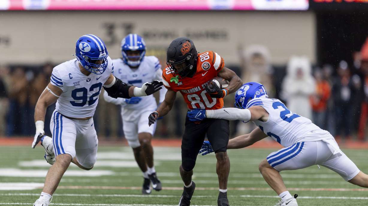 BYU safety Talan Alfrey (25) and defensive end Tyler Batty (92) tackle Oklahoma State wide receiver Brennan Presley (80) in the first half of an NCAA college football game Saturday, Nov. 25, 2023, in Stillwater, Okla.