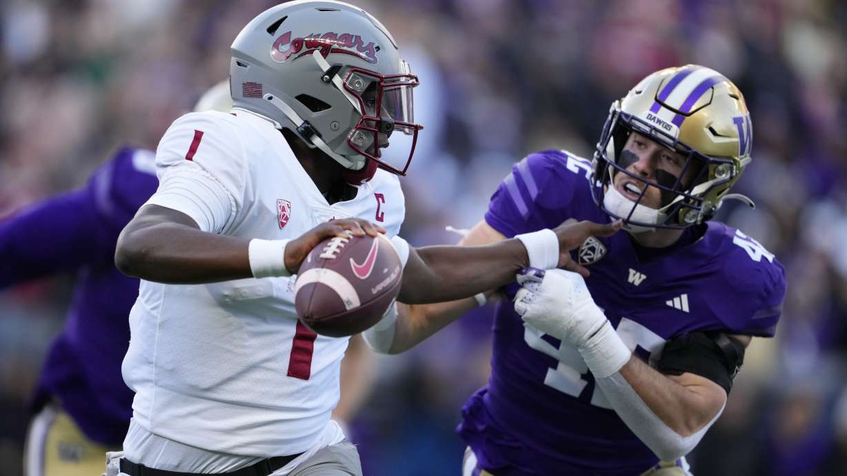 Washington State quarterback Cameron Ward blocks Washington linebacker Carson Bruener as he runs with the ball during the first half of an NCAA college football game, Saturday, Nov. 25, 2023, in Seattle.