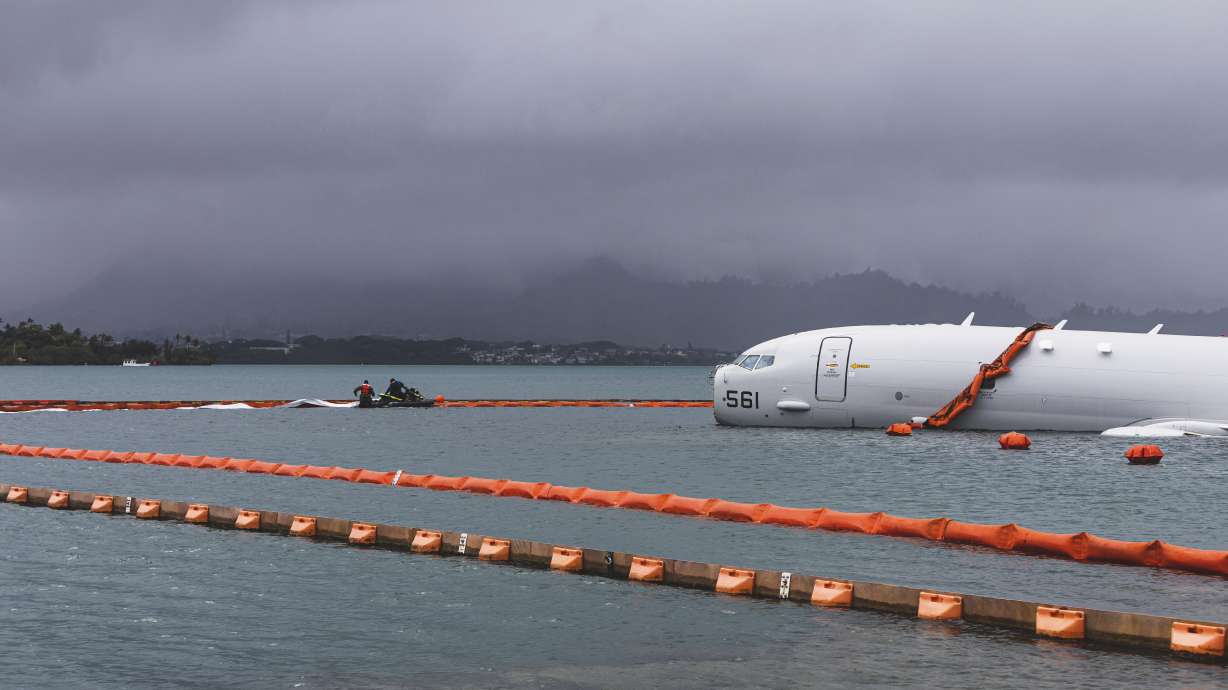 This Nov. 21 photo shows U.S. Navy sailors deploying temporary protective barriers around a downed Navy P-8A in waters just off the runway at Marine Corps Air Station Kaneohe Bay in Kaneohe Bay, Hawaii.