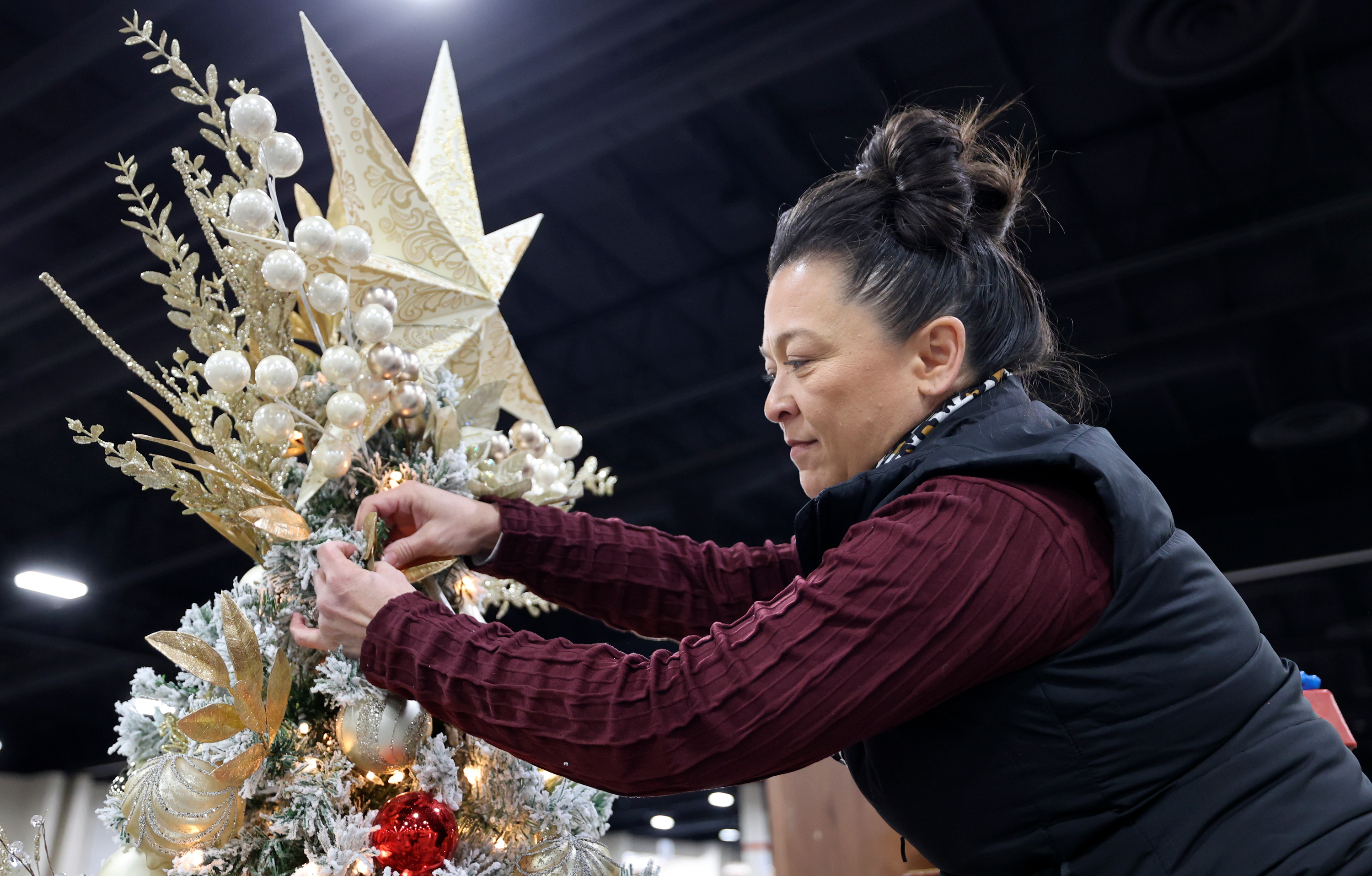 Becky Yamasaki puts finishing touches on a tree decorated in honor of Afu Fiefia at the 53rd annual Festival of Trees to benefit Intermountain Primary Children’s Hospital patients, at the Mountain America Expo Center in Sandy on Monday.