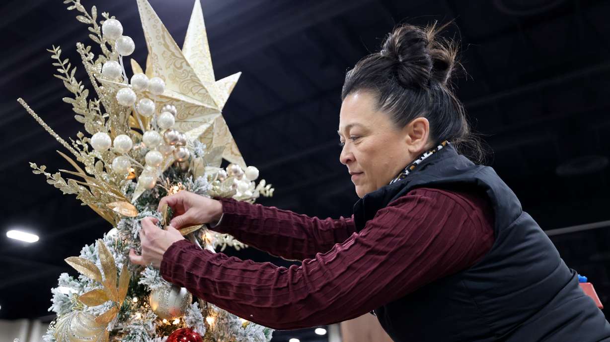 Becky Yamasaki puts finishing touches on a tree decorated in honor of Afu Fiefia at the 53rd annual Festival of Trees to benefit Intermountain Primary Children’s Hospital patients, at the Mountain America Expo Center in Sandy on Monday.