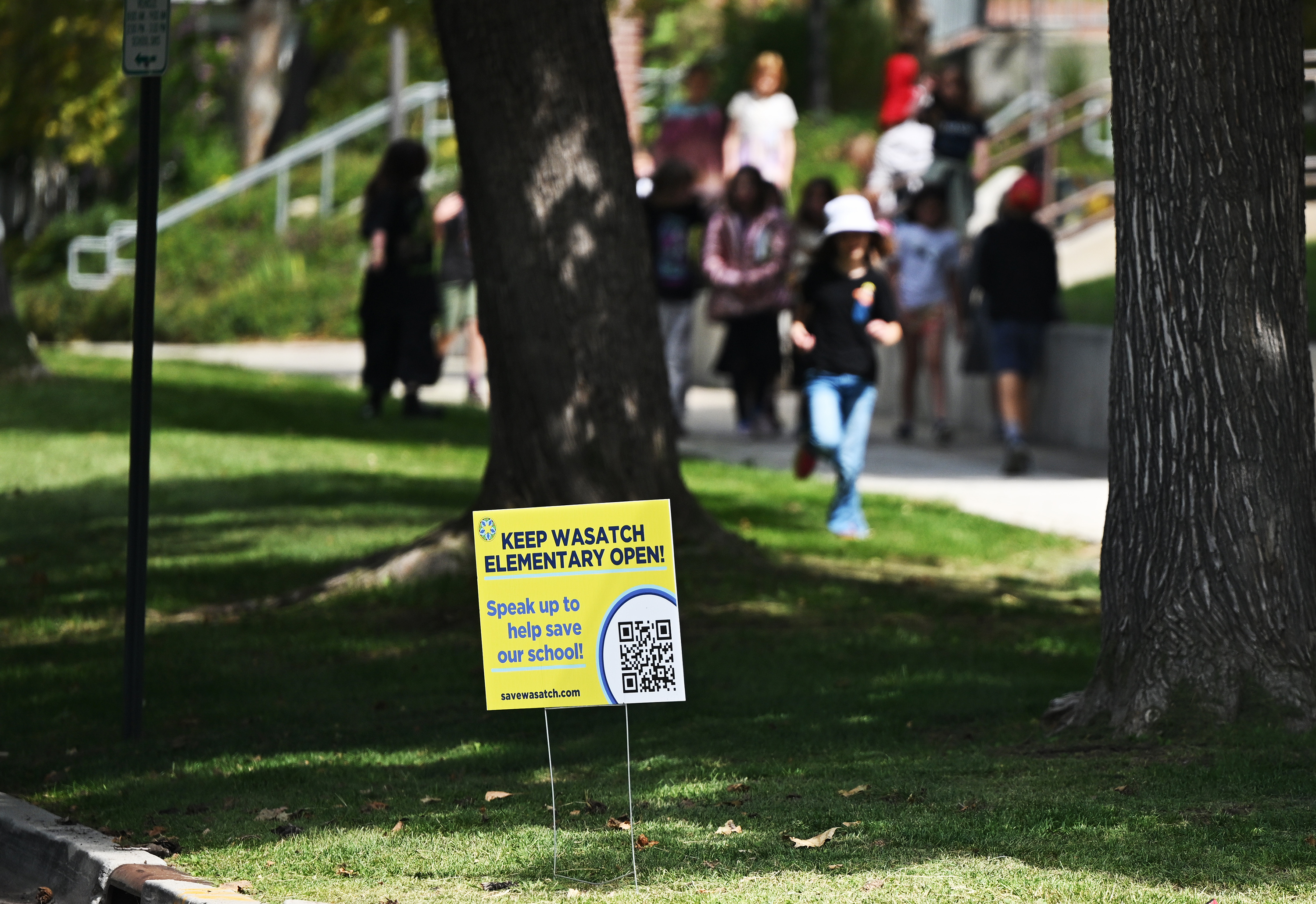 Students from Wasatch Elementary School hurry down the sidewalk for recess near a sign about the school's possible closure on Sept. 12. A new report says Salt Lake City's youth population is now the lowest it has been in more than a century.