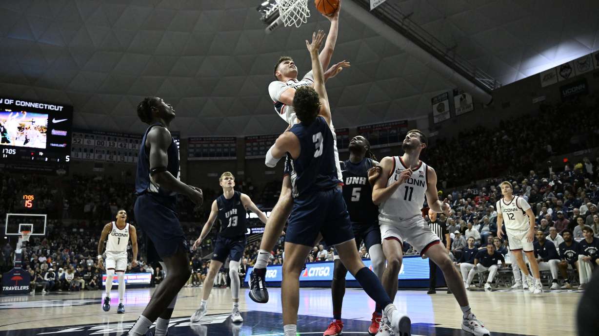 UConn center Donovan Clingan, top, makes a basket over New Hampshire's forward Jaxson Baker (3) in the first half of an NCAA college basketball game, Monday, Nov. 27, 2023, in Storrs, Conn.