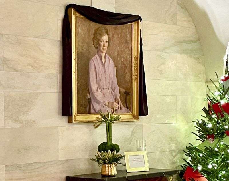 A black mourning drape over the oil canvas portrait of former first lady Rosalynn Carter, painted by American artist George Augusta in 1984, hangs in the White House, Monday in Washington.