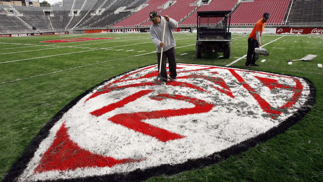Miguel Tena and Shawn Hughey work a sand and rubber mixture into a Pac-12 logo at Rice-Eccles Stadium in Salt Lake City on April 12, 2011. Washington State and Oregon State want control over conference assets.