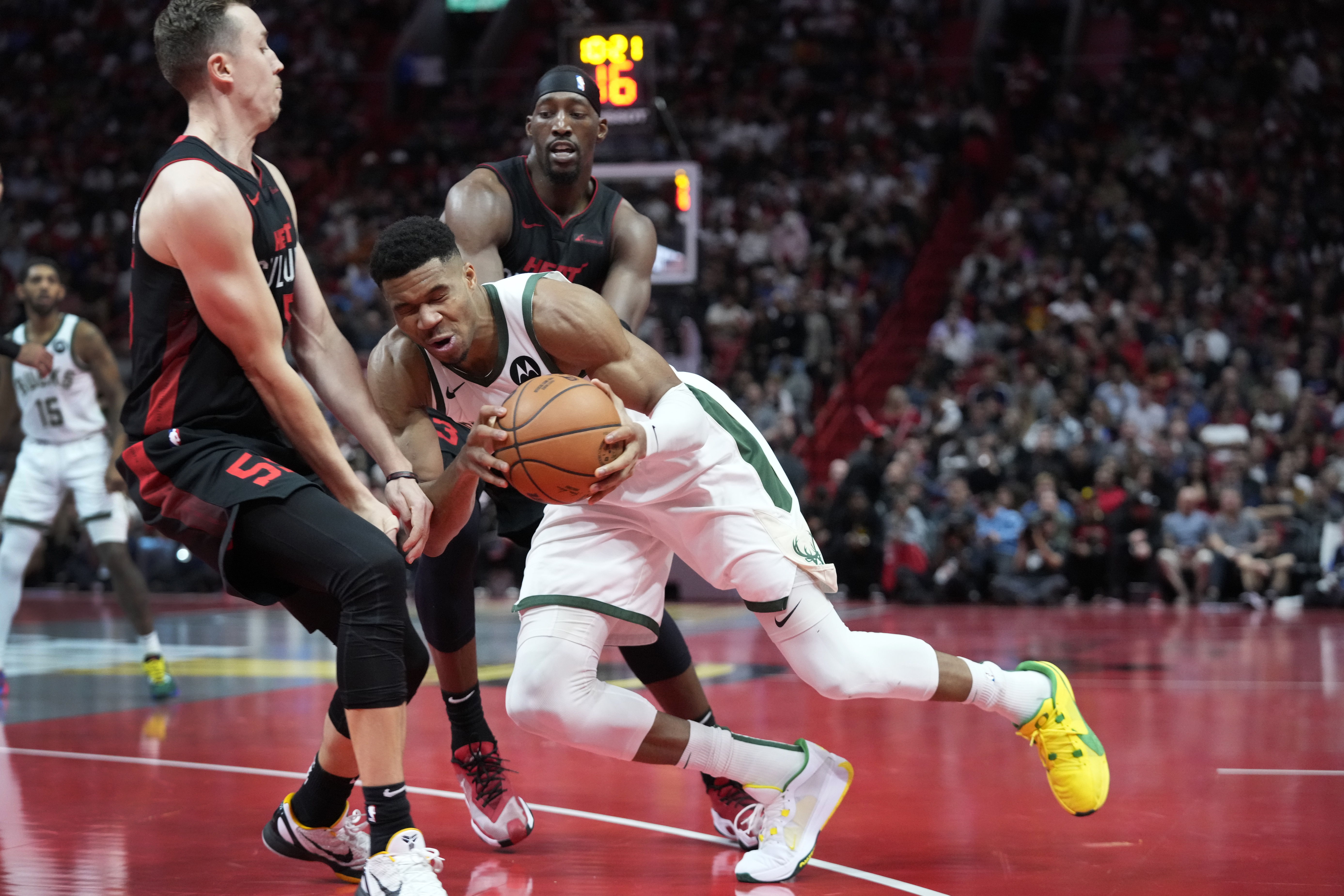 Milwaukee Bucks forward Giannis Antetokounmpo, center, collides with Miami Heat forward Duncan Robinson (55) as he drives past Robinson and center Bam Adebayo, rear, during the second half of an NBA basketball game, Tuesday, Nov. 28, 2023, in Miami.