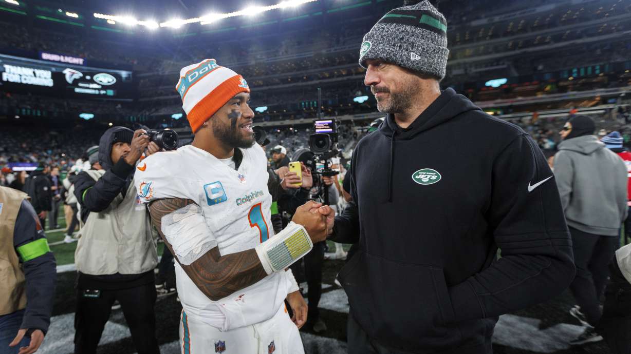 Miami Dolphins quarterback Tua Tagovailoa (1) interacts with New York Jets quarterback Aaron Rodgers (8) after the team's win over the New York Jets during an NFL football game Friday, Nov. 24, 2023, in East Rutherford, N.J.