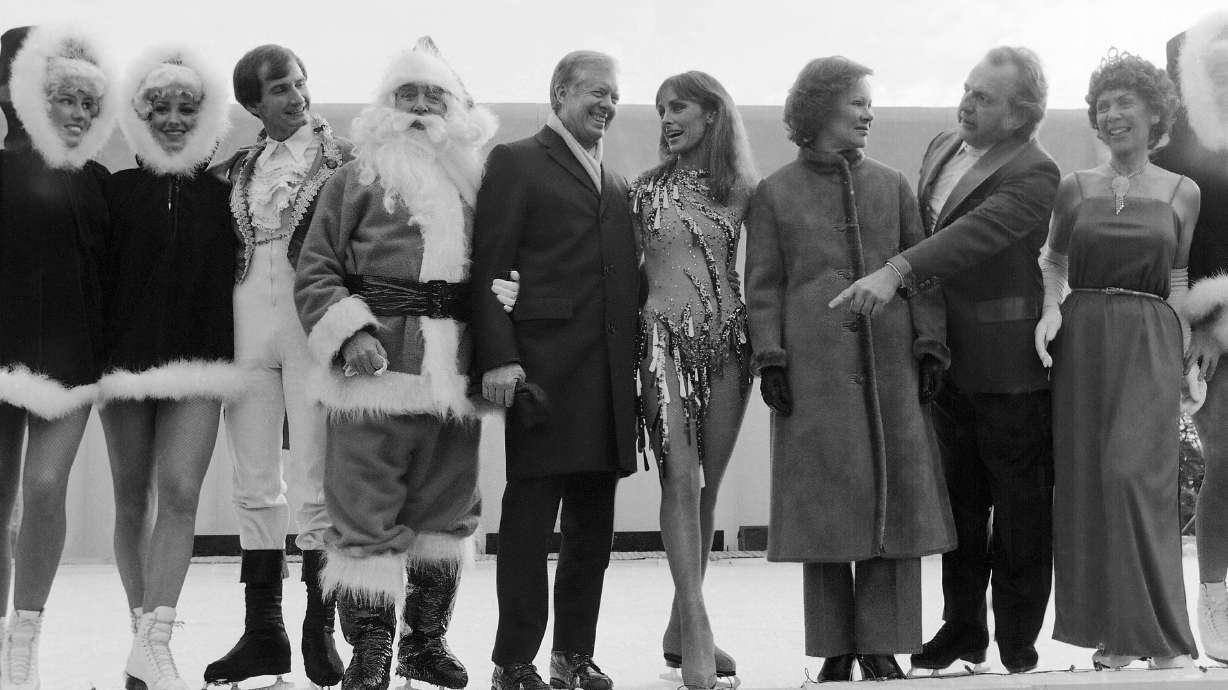 FILE - President Jimmy Carter calls for other performers to join himself, Santa Claus and ice skating star Peggy Fleming for pictures at a White House reception for U.S. Secret Service agents and military aides in Washington, Dec. 22, 1980. Jill Biden is bringing a holiday ice rink to the White House lawn for children to skate and play hockey during the holidays. The first lady was set to announce the rink after sunset on Wednesday. She was to be joined by 1988 Olympic figure skater Brian Boitano and the Snoopy character, among others. The White House says the rink will operate during December.