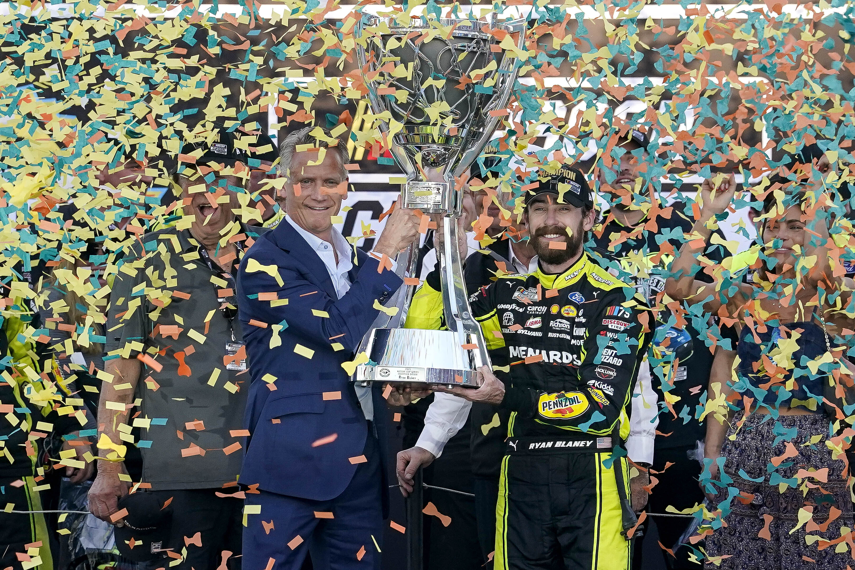 Ryan Blaney, center right, receives the NASCAR Cup Series Championship Cup from NASCAR president Steve Phelps, center left, after winning it at Phoenix Raceway, Sunday, Nov. 5, 2023, in Avondale, Ariz.
