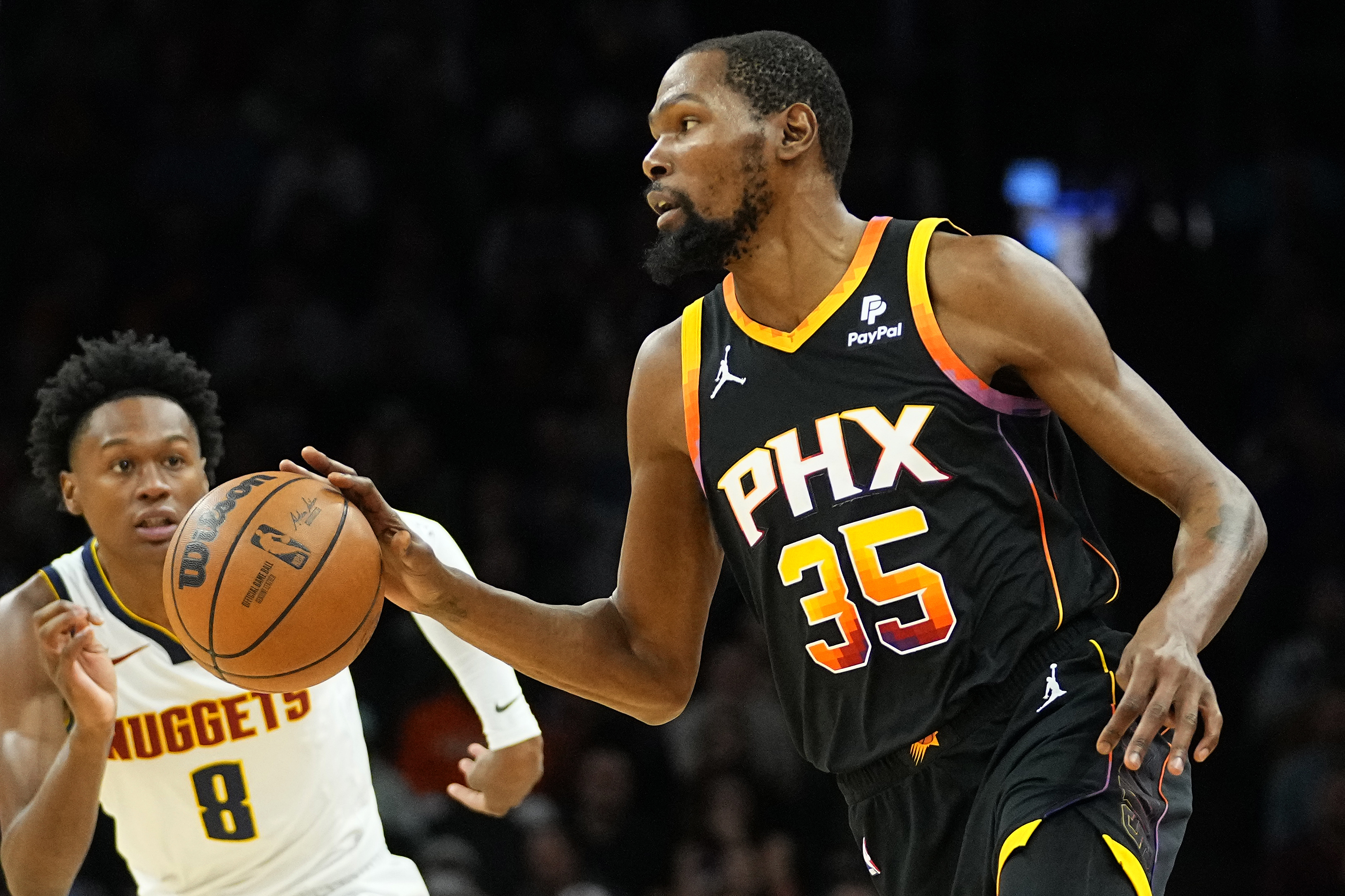 Phoenix Suns forward Kevin Durant (35) moves the ball up court as Denver Nuggets forward Peyton Watson (8) defends during the first half of an NBA basketball game, Friday, Dec. 1, 2023, in Phoenix.