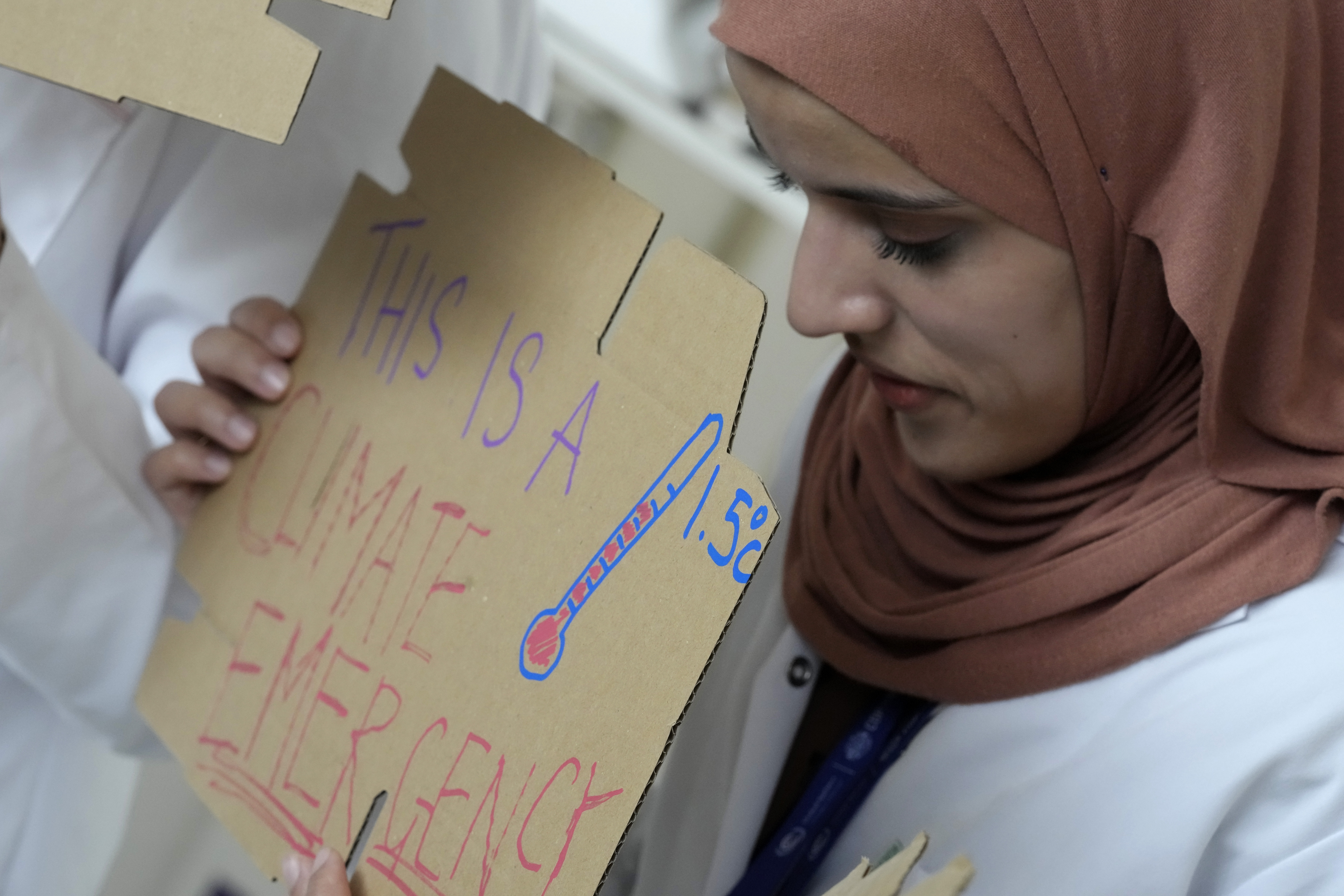 Sarah Neggazi holds a sign that reads "this is a climate emergency" during a demonstration at the COP28 U.N. Climate Summit, Sunday, in Dubai, United Arab Emirates.