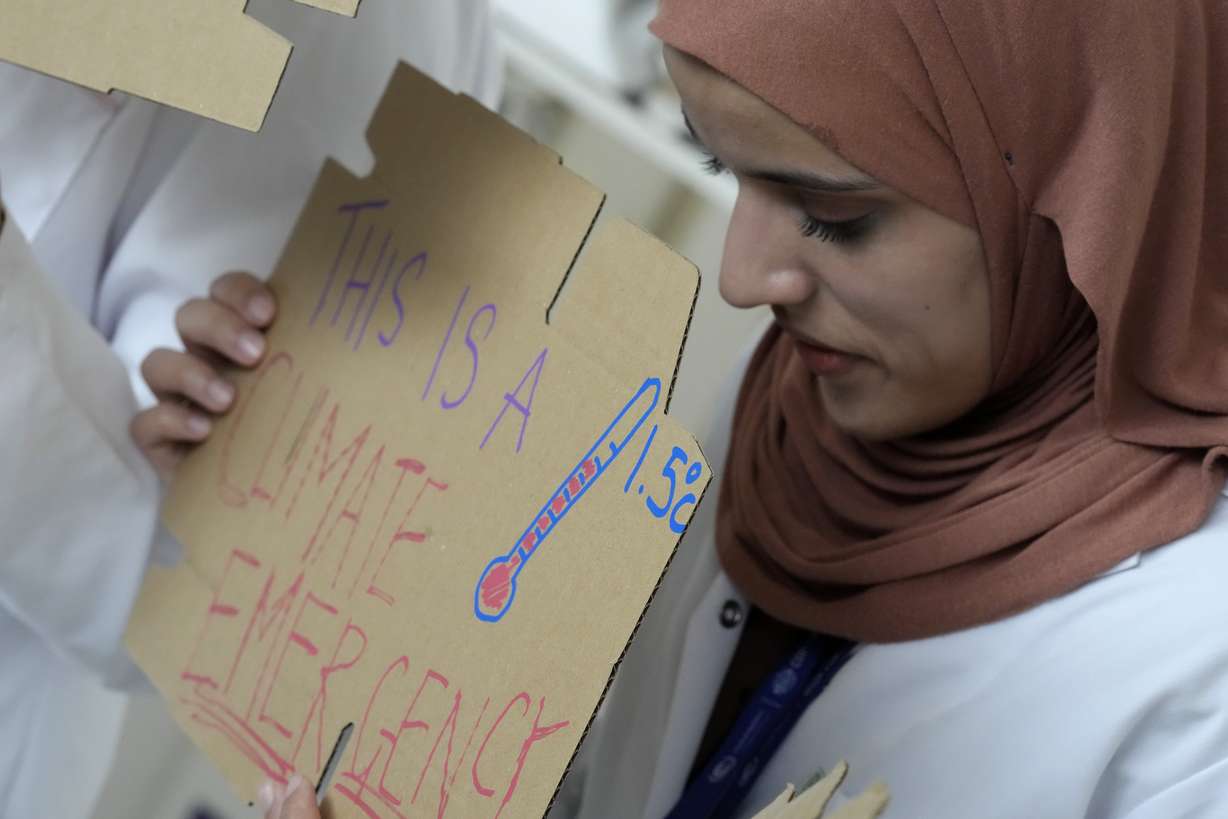 Sarah Neggazi holds a sign that reads "this is a climate emergency" during a demonstration at the COP28 U.N. Climate Summit, Sunday, in Dubai, United Arab Emirates.