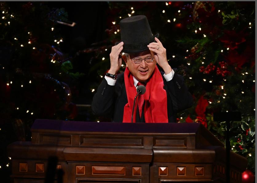 Elder Gerrit W. Gong, of the Quorum of the Twelve Apostles for The Church of Jesus Christ of Latter-day Saints, puts on a hat as he invites members to picture him as Ebenezer Scrooge during the First Presidency Christmas Devotional on Sunday.