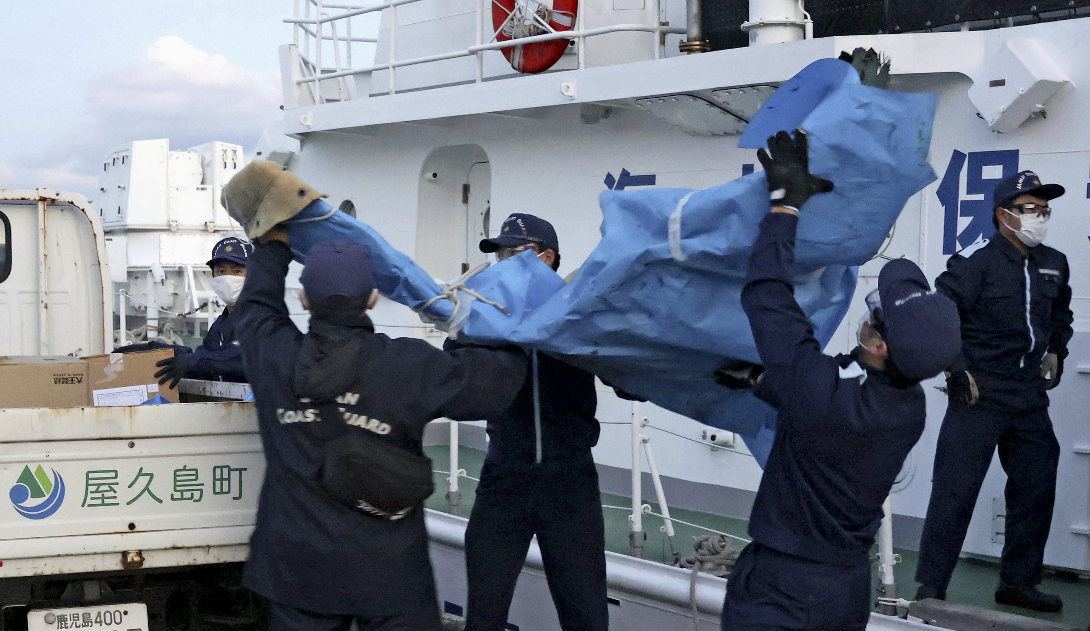 Members of the Japanese coast guard carry debris which is believed to be from the crashed U.S. military Osprey aircraft, at a port in Yakushima, Kagoshima prefecture, southern Japan, Monday.