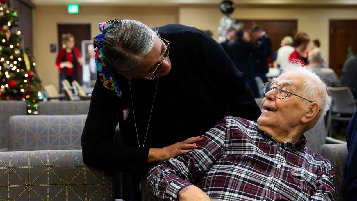 World War II veteran Wayne O. Ursenbach is greeted by his daughter-in-law Kathy Ursenbach at a special social hour with community residents held to celebrate his 100th birthday at Sagewood at Daybreak in South Jordan on Monday.