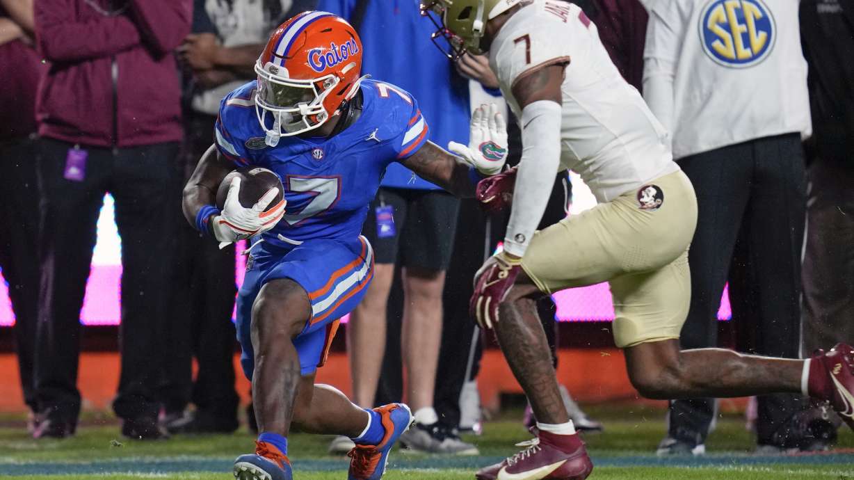 Florida running back Trevor Etienne, left, gains yardage before Florida State defensive back Jarrian Jones, right, can stop him during the first half of an NCAA college football game Saturday, Nov. 25, 2023, in Gainesville, Fla.