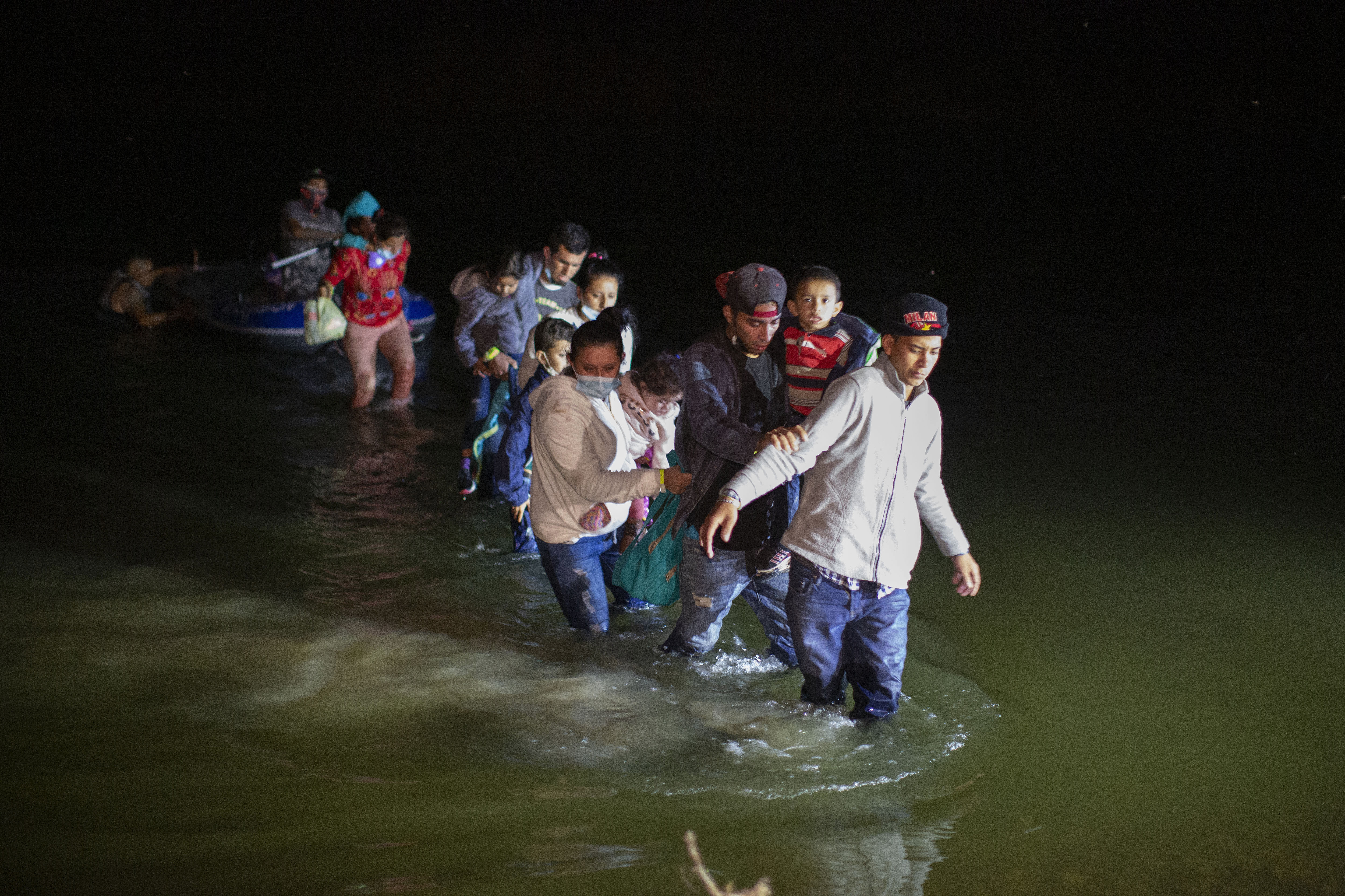 Migrant families wade through shallow waters toward Roma, Texas, March 24, 2021. A federal judge was poised Friday to prohibit the separation of families at the border for purposes of deterring immigration for eight years.
