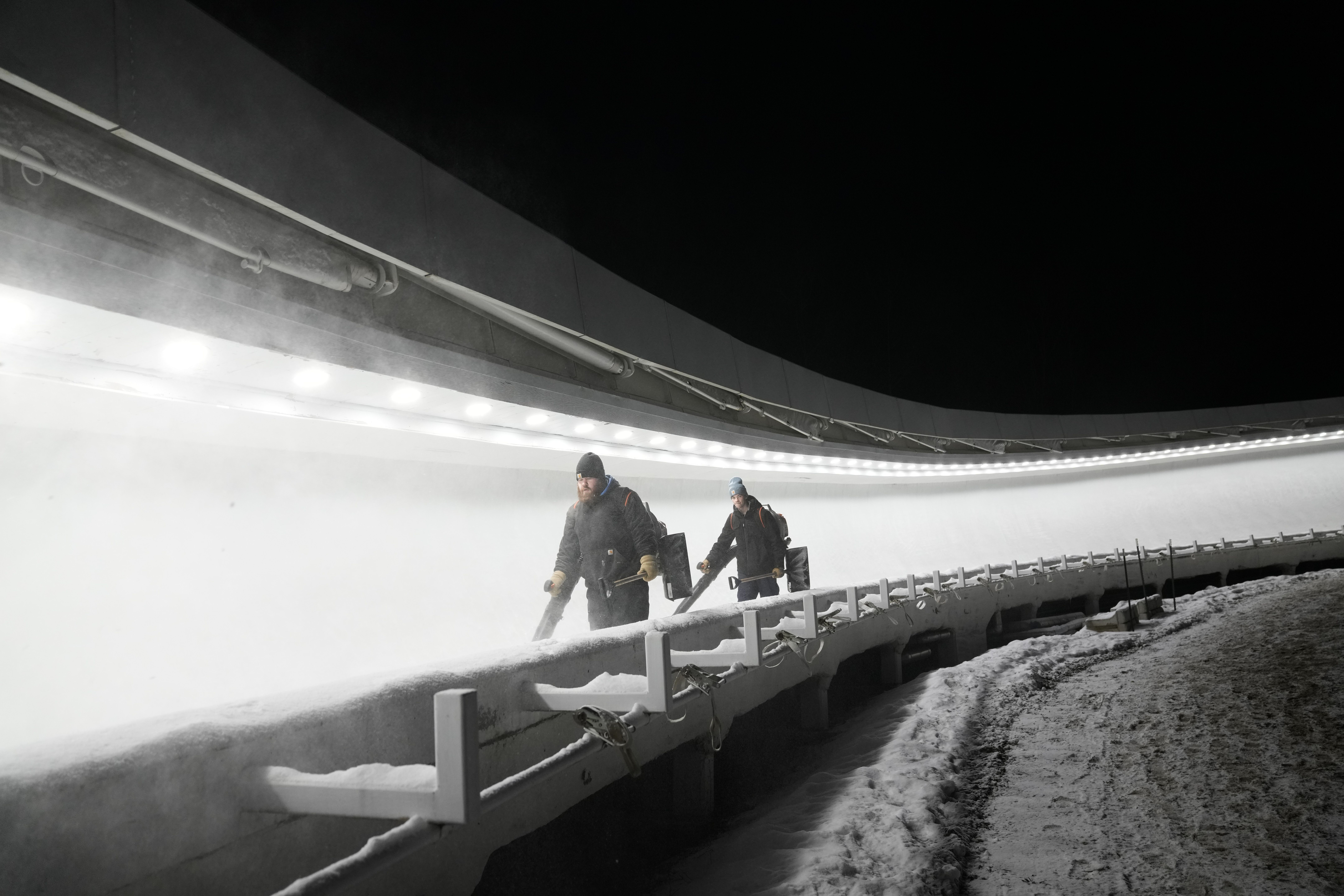 Workers perform maintenance on the track for the luge World Cup in Lake Placid, N.Y., Thursday. Lake Placid is bidding to hold sliding sports for the 2026 Winter Games because Italian organizers don’t have a track.