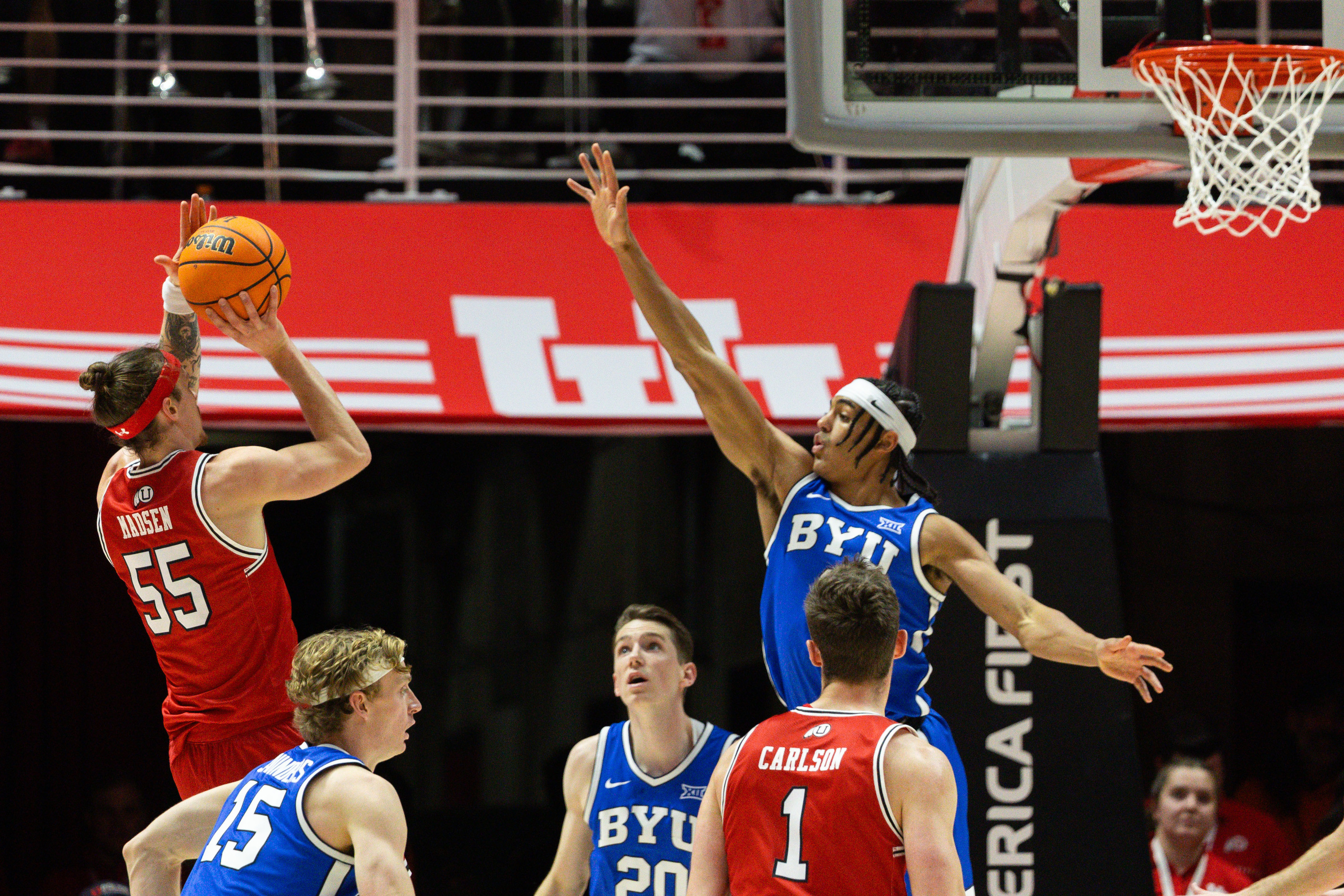 Utah guard Gabe Madsen (55) shoots the ball with Brigham Young guard Trey Stewart (1) jumping to try and block during an NCAA men’s basketball game at the Huntsman Center in Salt Lake City on Saturday, Dec. 9, 2023.