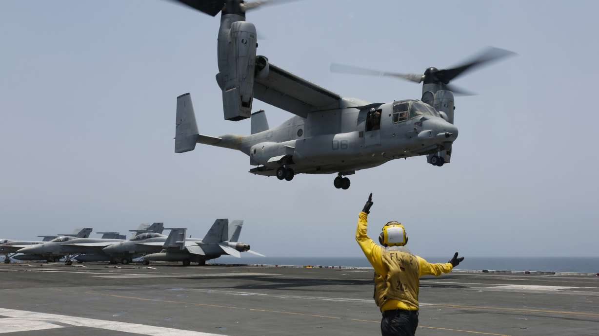 In this image provided by the U.S. Navy, Aviation Boatswain's Mate 2nd Class Nicholas Hawkins, signals an MV-22 Osprey to land on the flight deck of the USS Abraham Lincoln in the Arabian Sea on May 17, 2019. Navy divers have recovered the remains of the seventh of the eight crew members from a U.S. military Osprey aircraft that crashed off southern Japan during a training mission.