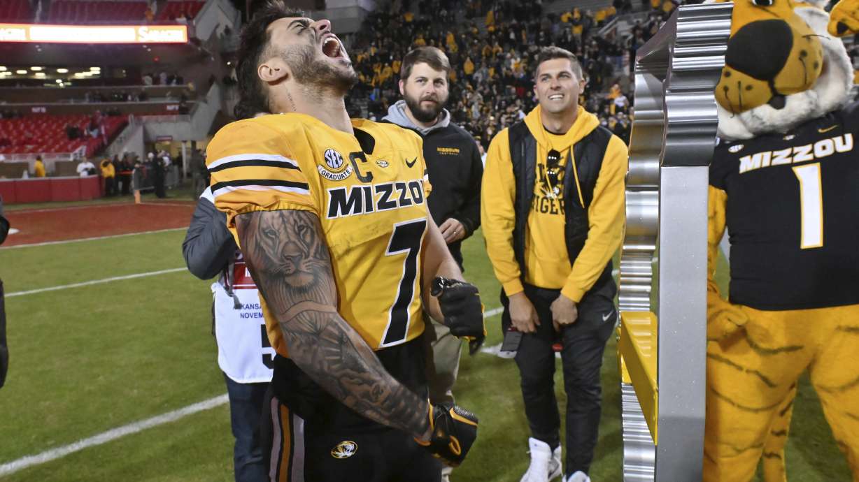 Missouri running back Cody Schrader (7) celebrates next to the Battle Line trophy after the team's win over Arkansas in an NCAA college football game Friday, Nov. 24, 2023, in Fayetteville, Ark.