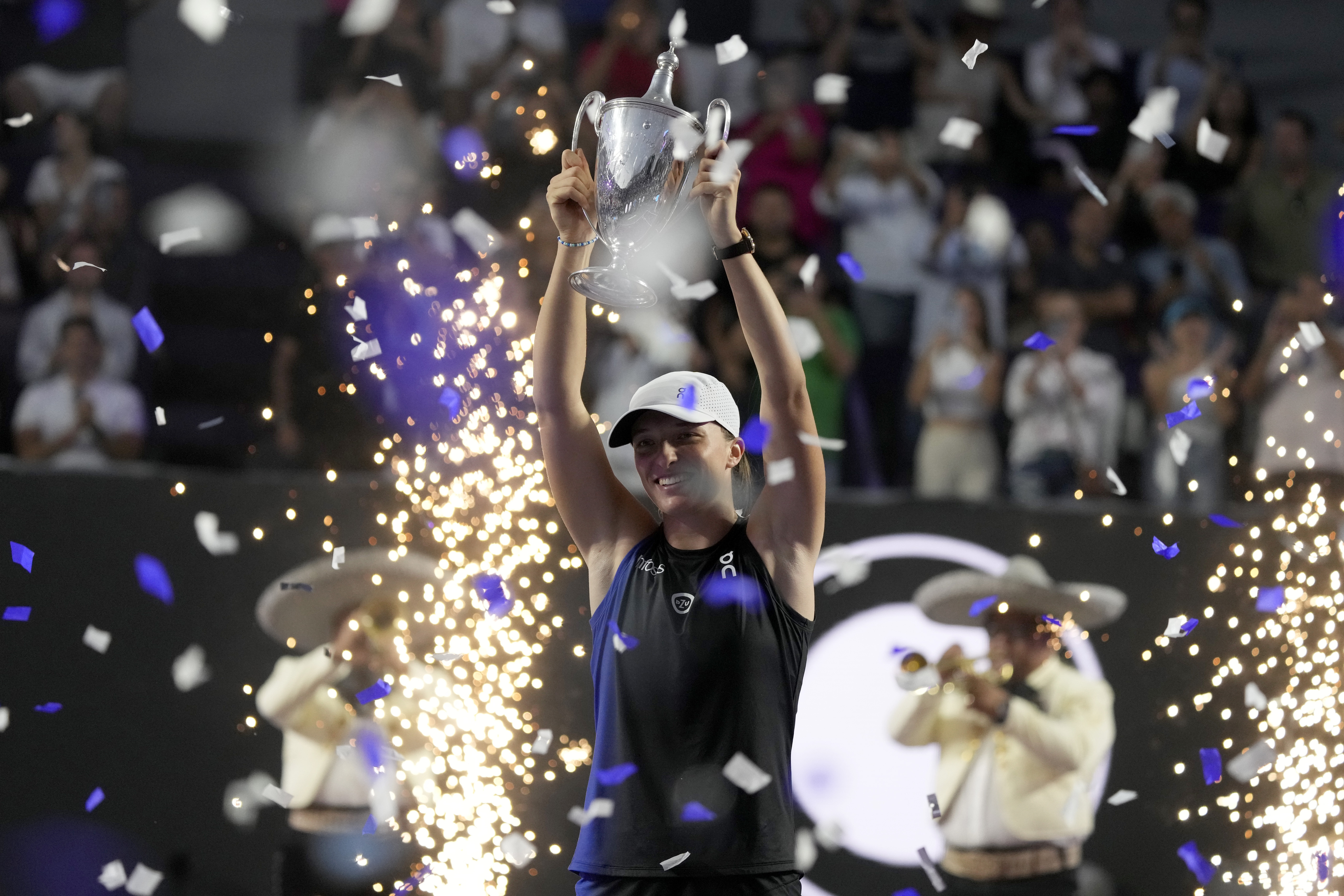 FILE - Poland's Iga Swiatek holds her trophy after her victory over Jessica Pegula, of the United States, in the women's singles final of the WTA Finals tennis championships, in Cancun, Mexico, Monday, Nov. 6, 2023. Swiatek’s second consecutive season-ending No. 1 ranking helped her collect a second consecutive WTA Player of the Year award on Monday, Dec. 11, 2023, making her the first woman since Serena Williams to claim that honor twice in a row.