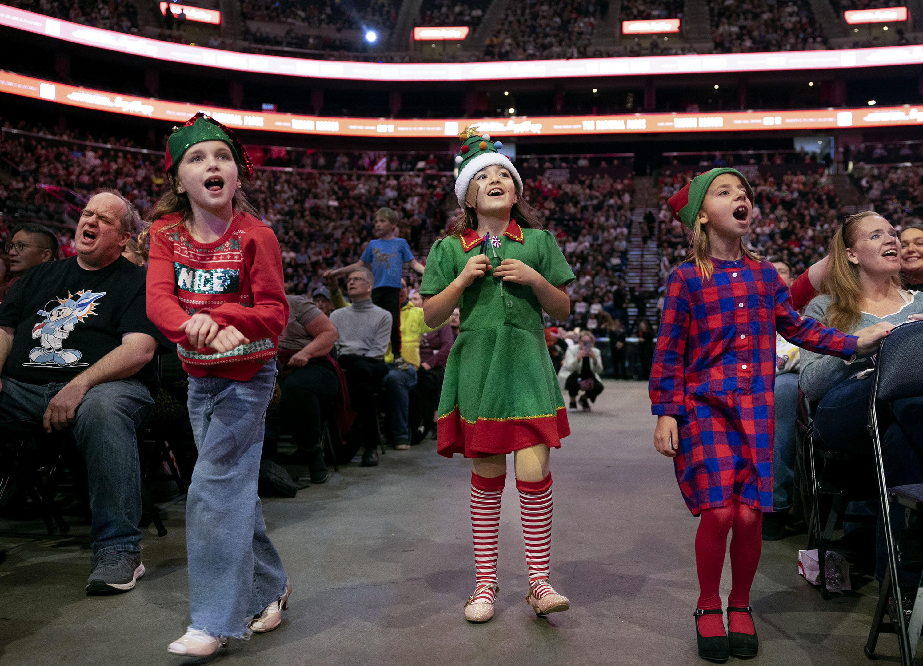 Ruby Yates, Aria Holbrook and Millie Airhart of Salt Lake City participate in the 39th Annual Holiday Sing-Along at the Delta Center in Salt Lake City on Monday.
