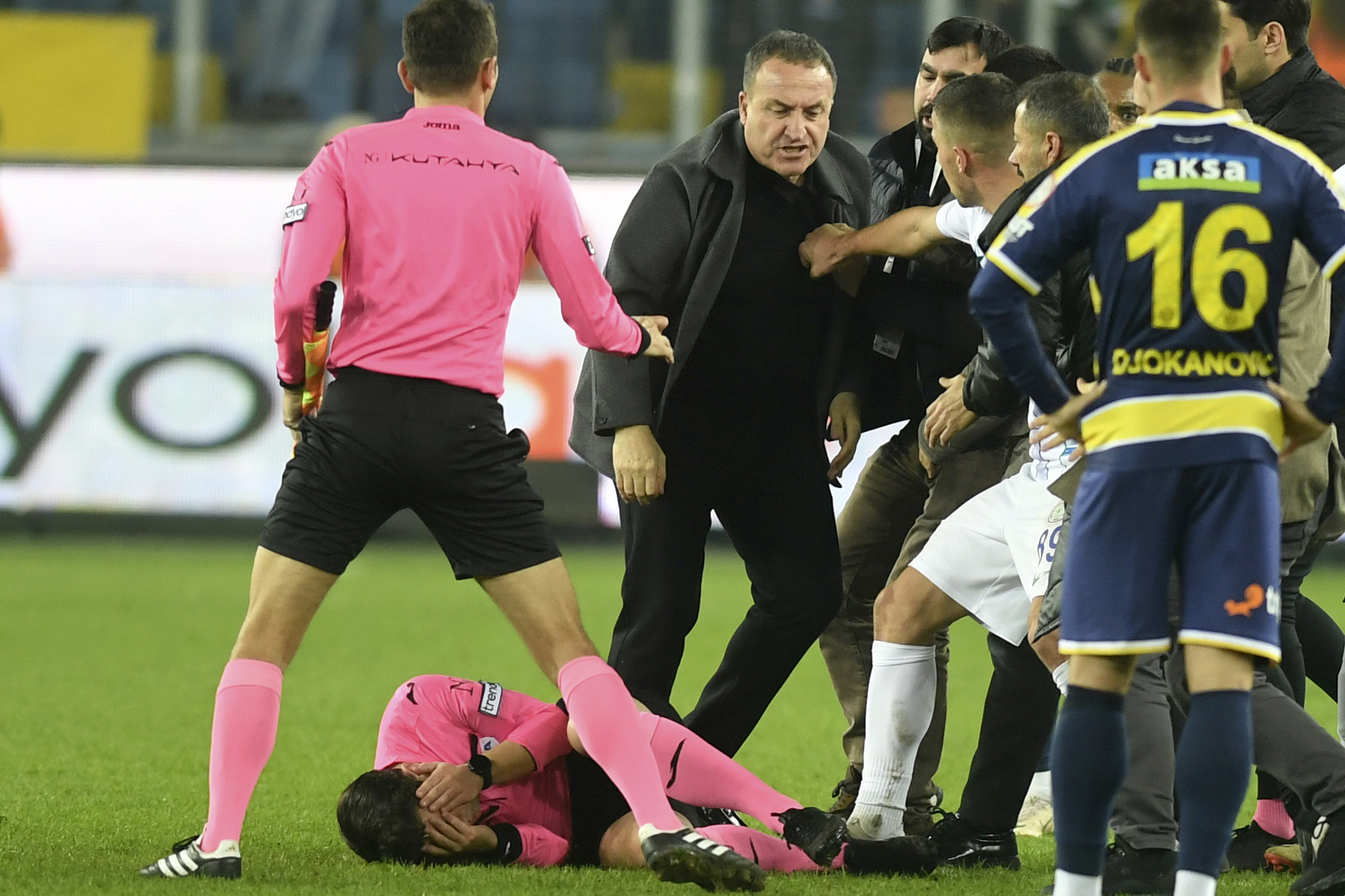 Referee Halil Umut Meler holds his face as he lies on the ground after being punched by MKE Ankaragucu president Faruk Koca, center, at the end of the Turkish Super Lig soccer match between MKE Ankaragucu and Caykur Rizespor in Ankara, Monday, Dec. 11, 2023. The Turkish Football Federation has suspended all league games in the country after a club president punched the referee in the face at the end of a top-flight match. Koca was arrested Tuesday, Dec. 12, 2023, along with two other people on charges of injuring a public official following questioning by prosecutors.