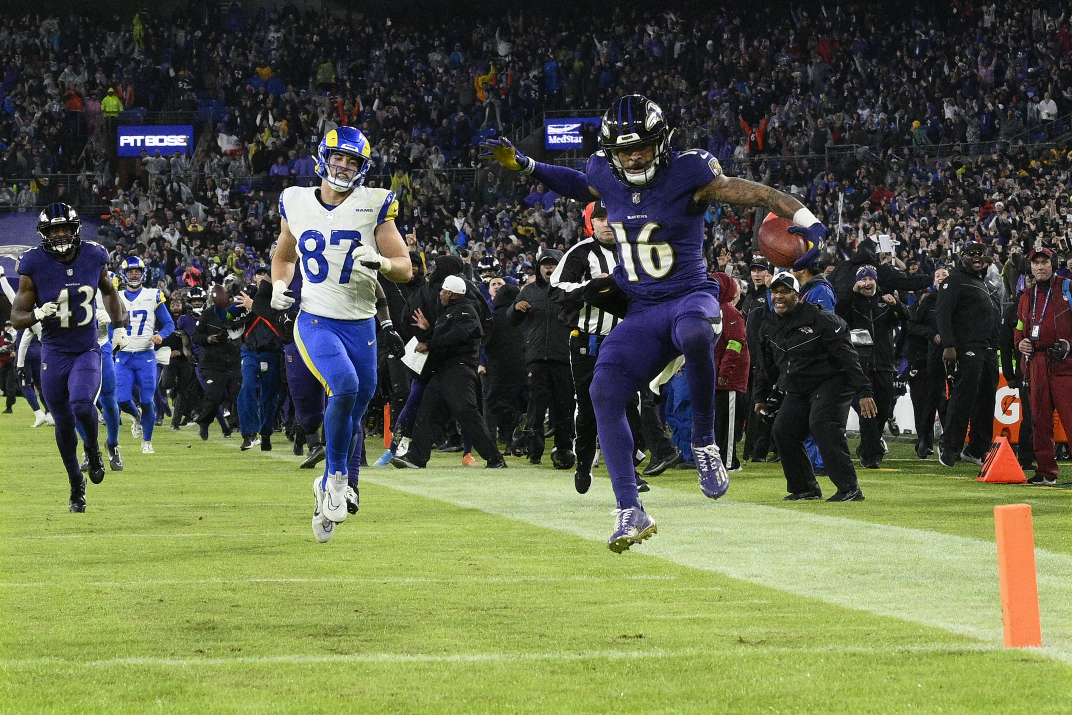 Baltimore Ravens punt returner Tylan Wallace (16) starts to celebrates as he returns a punt for a game-winning touchdown as Los Angeles Rams tight end Davis Allen (87) looks on during overtime of an NFL football game Sunday, Dec. 10, 2023, in Baltimore. The Ravens won 37-31. 