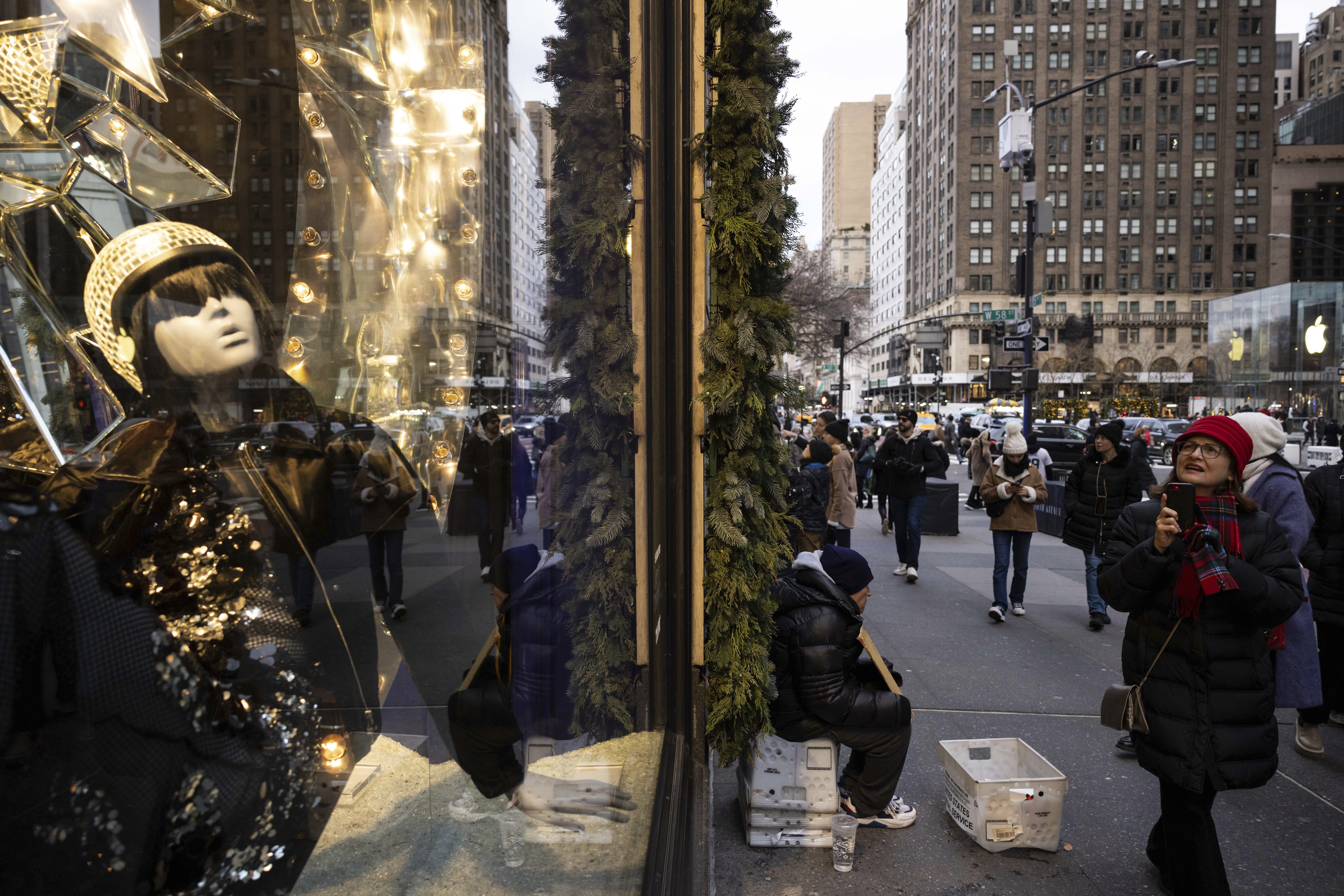 Passersby look at store window displays on the 5th Avenue, Dec. 11, in New York. On Thursday, the Commerce Department releases U.S. retail sales data for November.