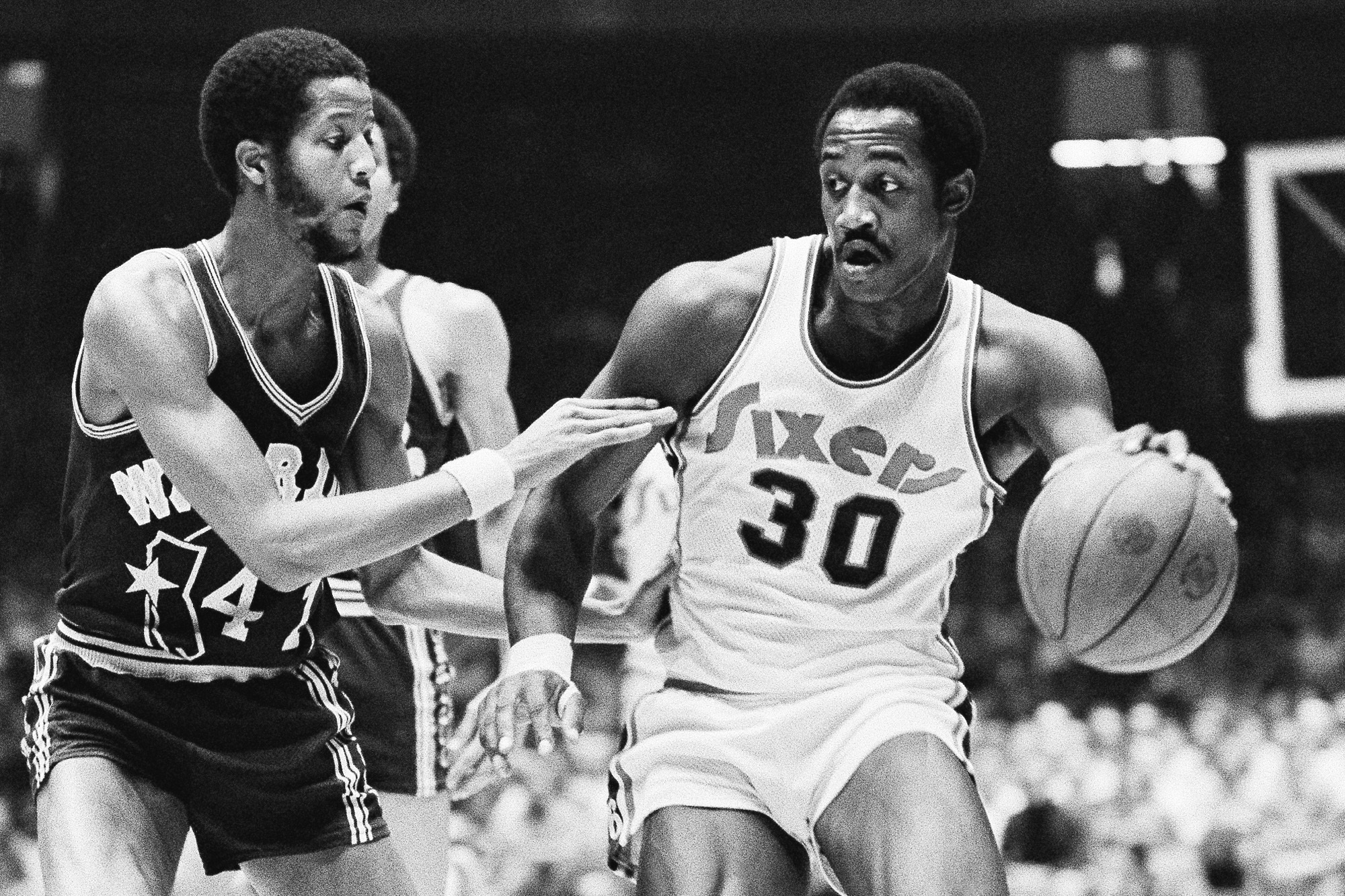 FILE - Golden State Warriors Jamaal Wilkes (41) tries to keep 76ers forward George McGinnis (30) from getting closer to the basket during the first half of NBA game on Tuesday, Nov. 25, 1975 in Philadelphia. McGinnis, a Hall of Fame forward who was a two-time ABA champion and three-time All-Star in the NBA and ABA, died Thursday, Dec. 14, 2023 He was 73. 