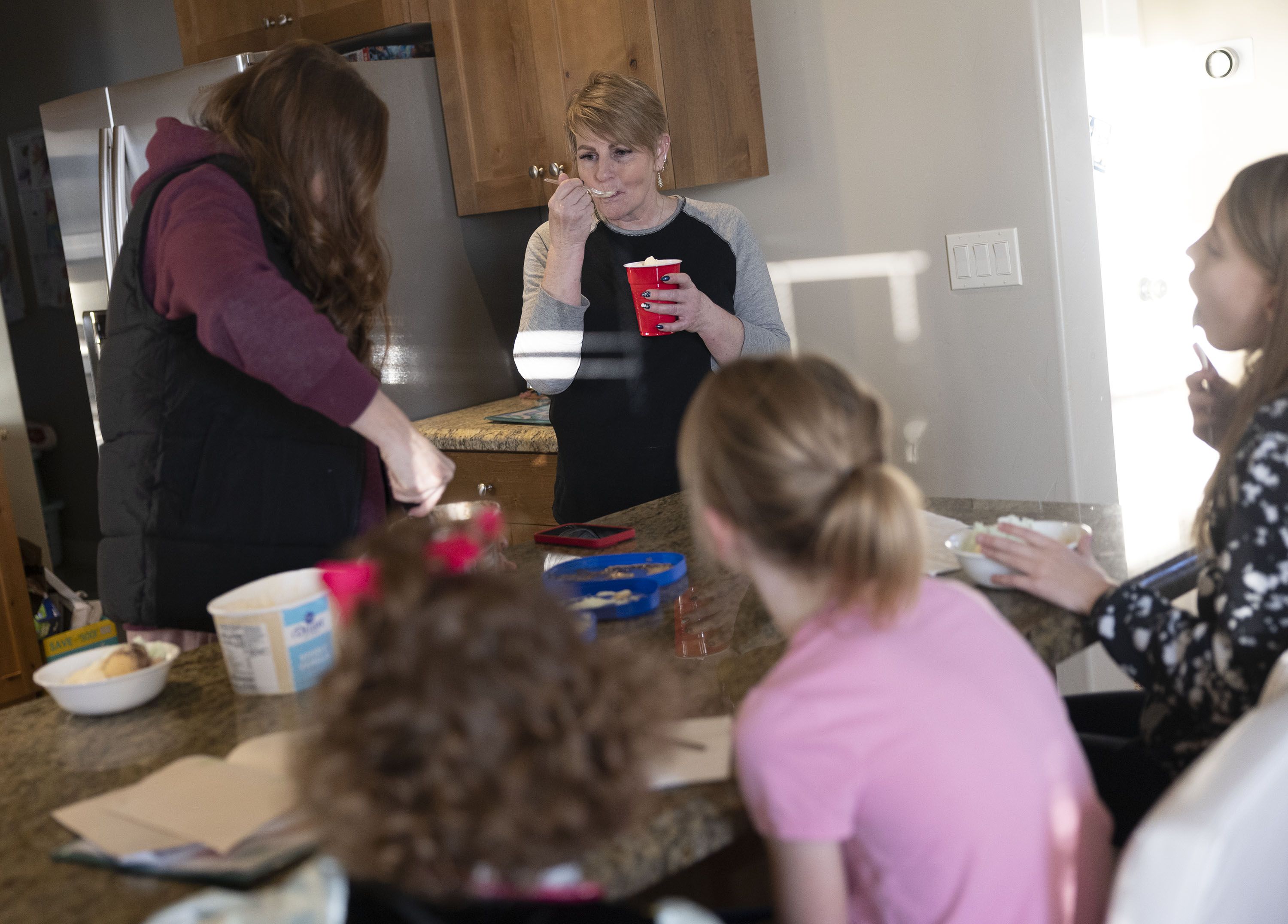 Cyd Overton, the Baker family’s nanny, eats ice cream with the kids after school at their Layton home on Wednesday. Overton helps out four days a week while Baker is at work.