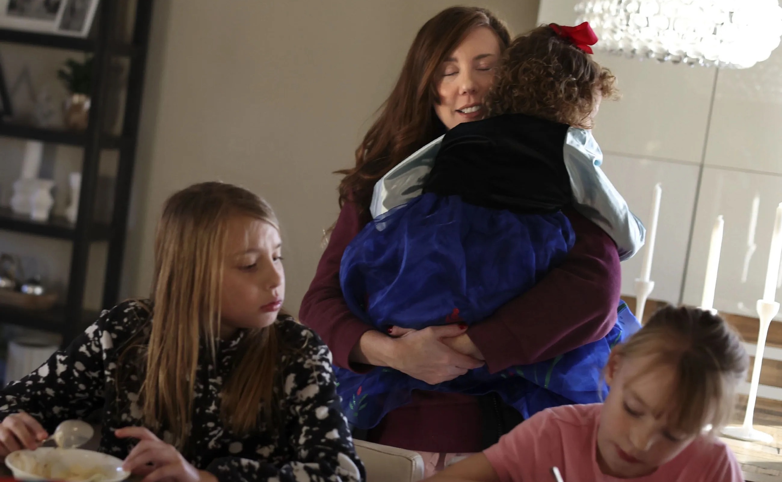 Shay Baker hugs her youngest daughter, Junie, 3, as Holland, 9, and Maxwell, 7, have an after-school snack at their Layton home on Wednesday. A new report examines the rate of labor force participation by women in Utah.