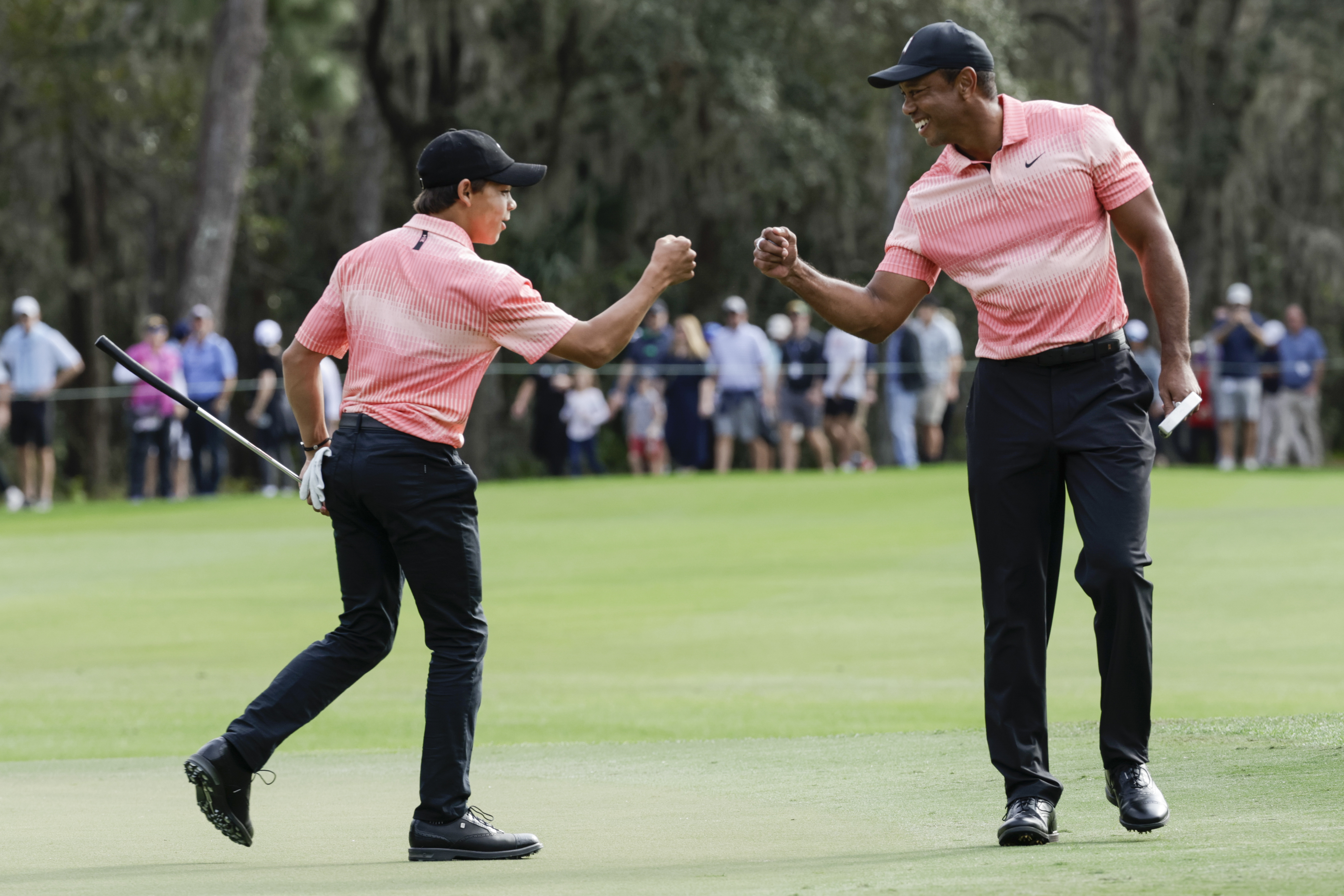 FILE - Tiger Woods, right, fist bumps his son Charlie Woods, left, after finishing the ninth hole during the first round of the PNC Championship golf tournament Saturday, Dec. 17, 2022, in Orlando, Fla. Tiger Woods is feeling good enough that he turned down a cart and chose to walk 18 holes in the PNC Championship pro-am. His 14-year-old son, Charlie, is hitting it long enough that he had to move back a tee.