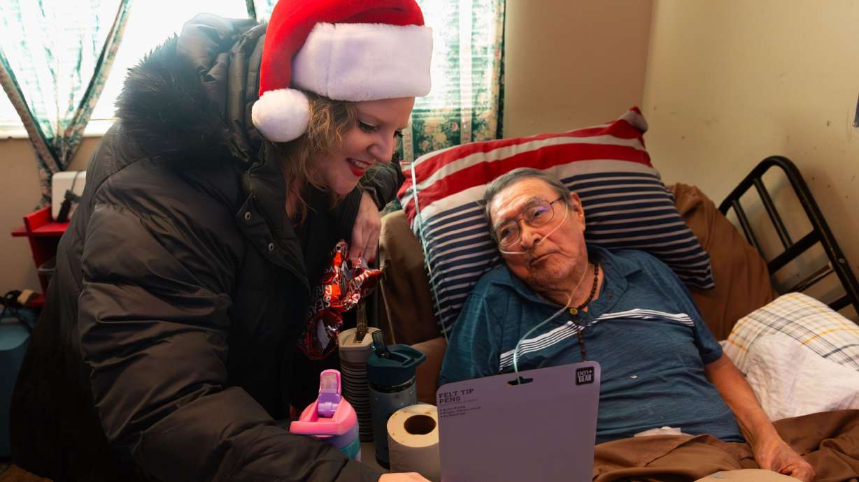 Sheiree Miller, client care coordinator for Home Instead, delivers a Christmas present to Ray Perry Bennett, 91, as part of the Santa to a Senior program at his home in Taylorsville on Thursday.
