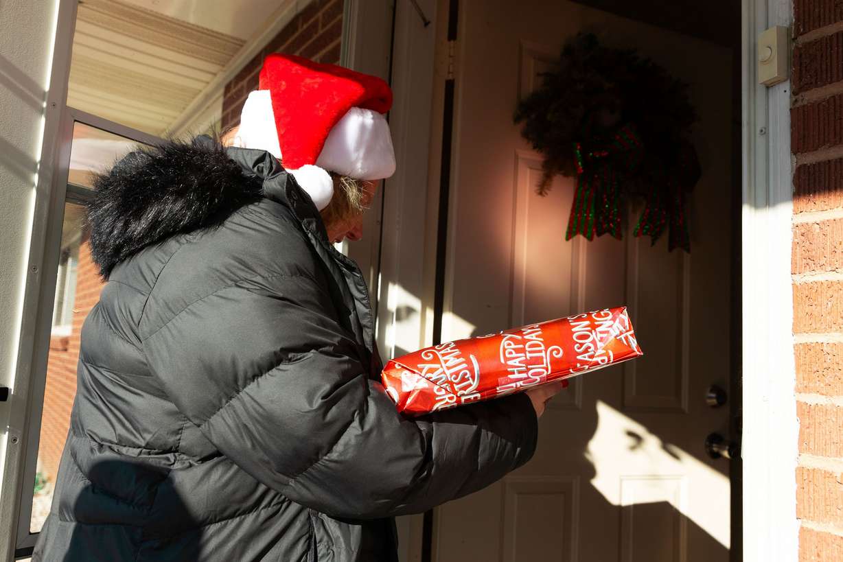 Sheiree Miller, client care coordinator for Home Instead, delivers a Christmas present to Ray Perry Bennett, 91, as part of the Santa to a Senior program at his home in Taylorsville on Thursday.