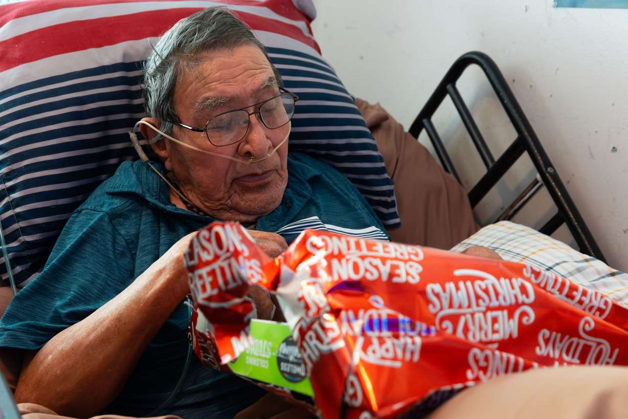 Ray Perry Bennett, 91, opens a Christmas present from the Santa to a Senior program at his home in Taylorsville on Thursday.
