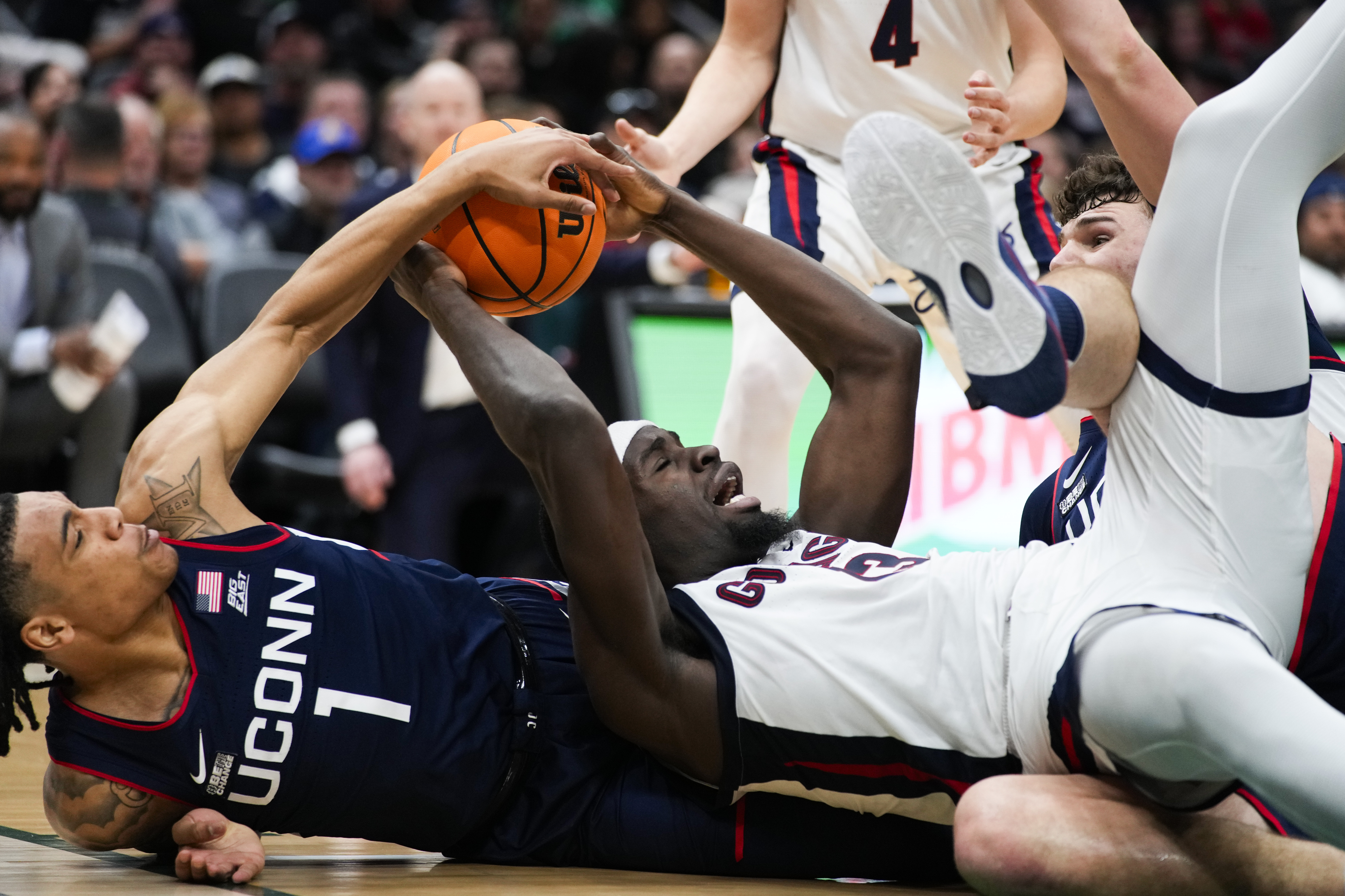 Gonzaga forward Graham Ike, lower right, tries to hold on to the ball as he falls to the court between UConn guard Solomon Ball (1) and center Donovan Clingan, right, during the first half of an NCAA college basketball game Friday, Dec. 15, 2023, in Seattle. 