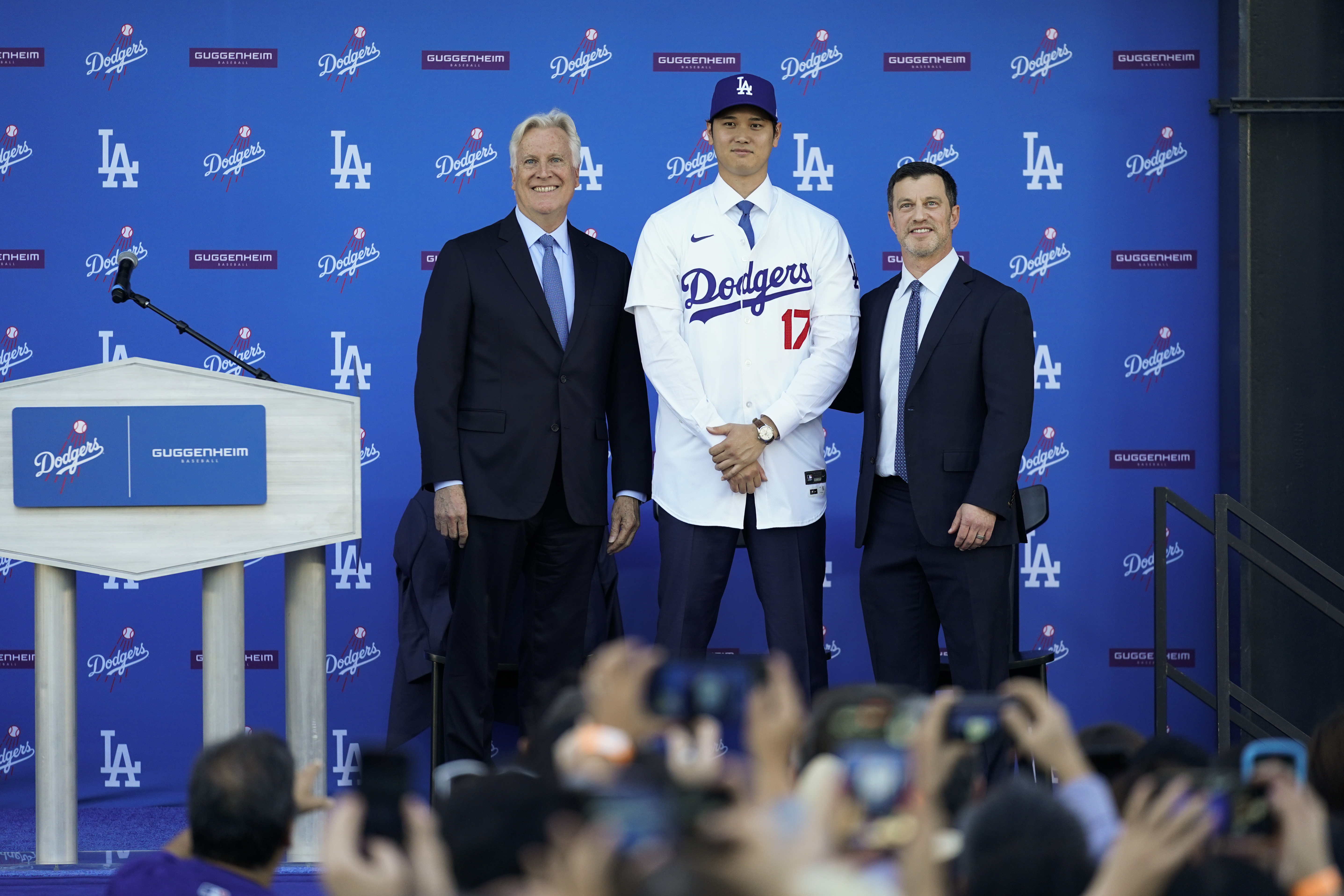 Los Angeles Dodgers' Shohei Ohtani, center, poses for a photo with owner and chairman Mark Walter, left, and president of baseball operations Andrew Friedman applaud during a news conference at Dodger Stadium Thursday, Dec. 14, 2023, in Los Angeles. 