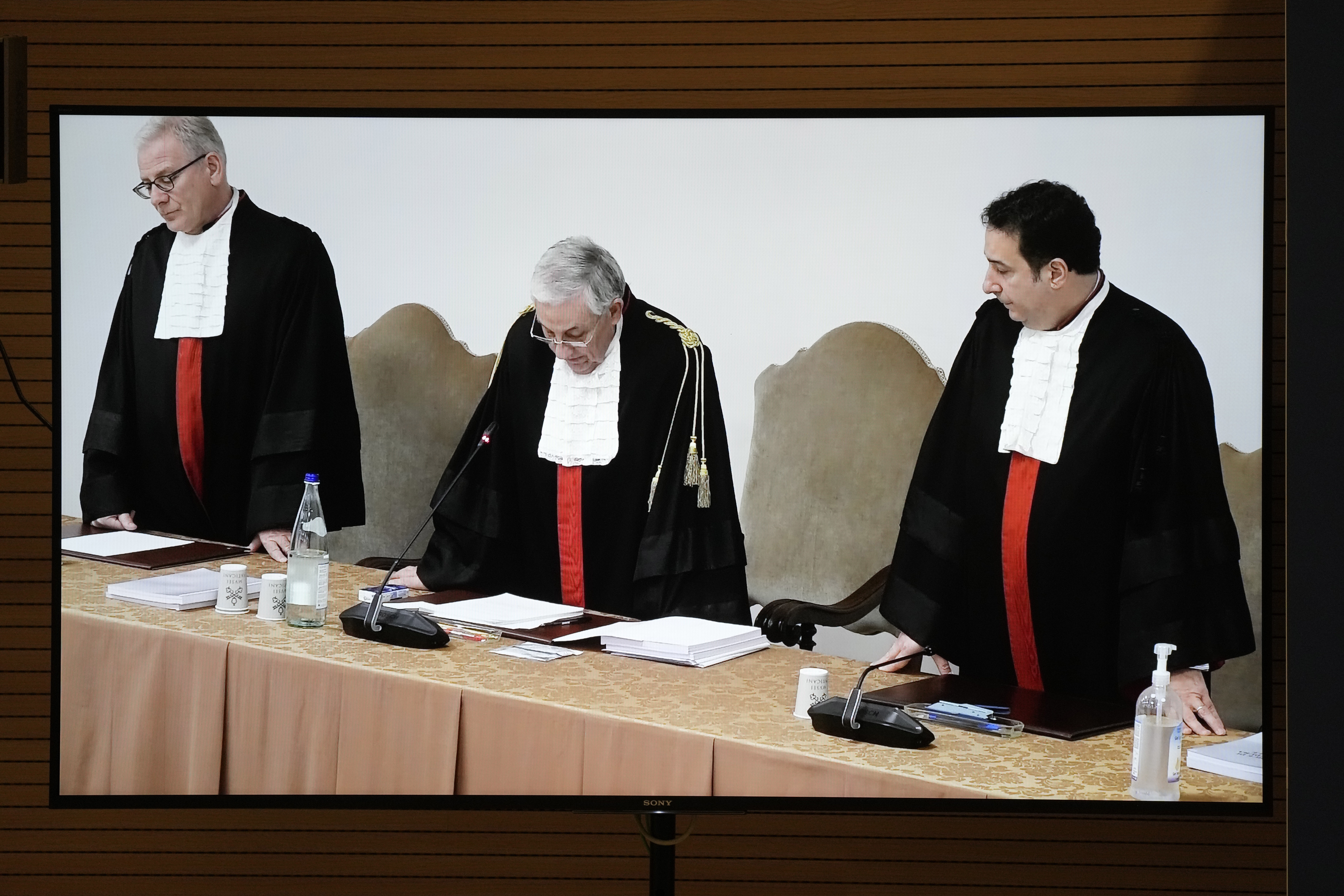 A screen shows Vatican tribunal president Giuseppe Pignatone reading the verdict of a trial against Cardinal Angelo Becciu and nine other defendants, in the Vatican press room, Saturday.